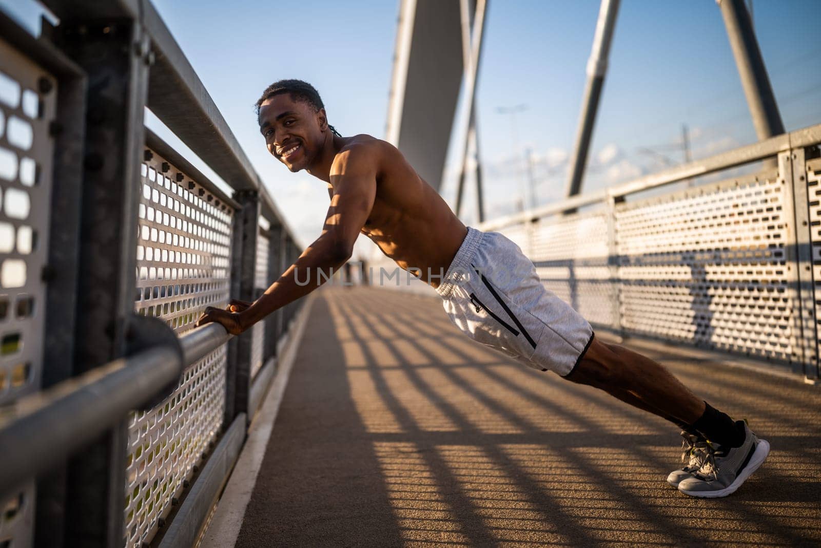 Young  man is exercising on the bridge in the city. He is doing push-ups.