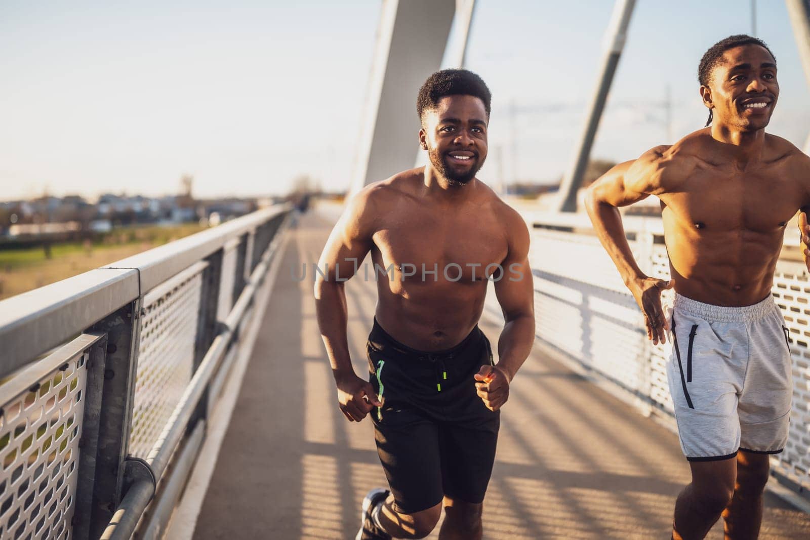 Two friends are jogging on the bridge in the city.