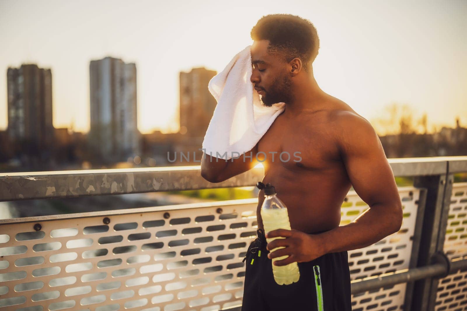 Tired young  man  wipes the sweat from his face after jogging by djoronimo