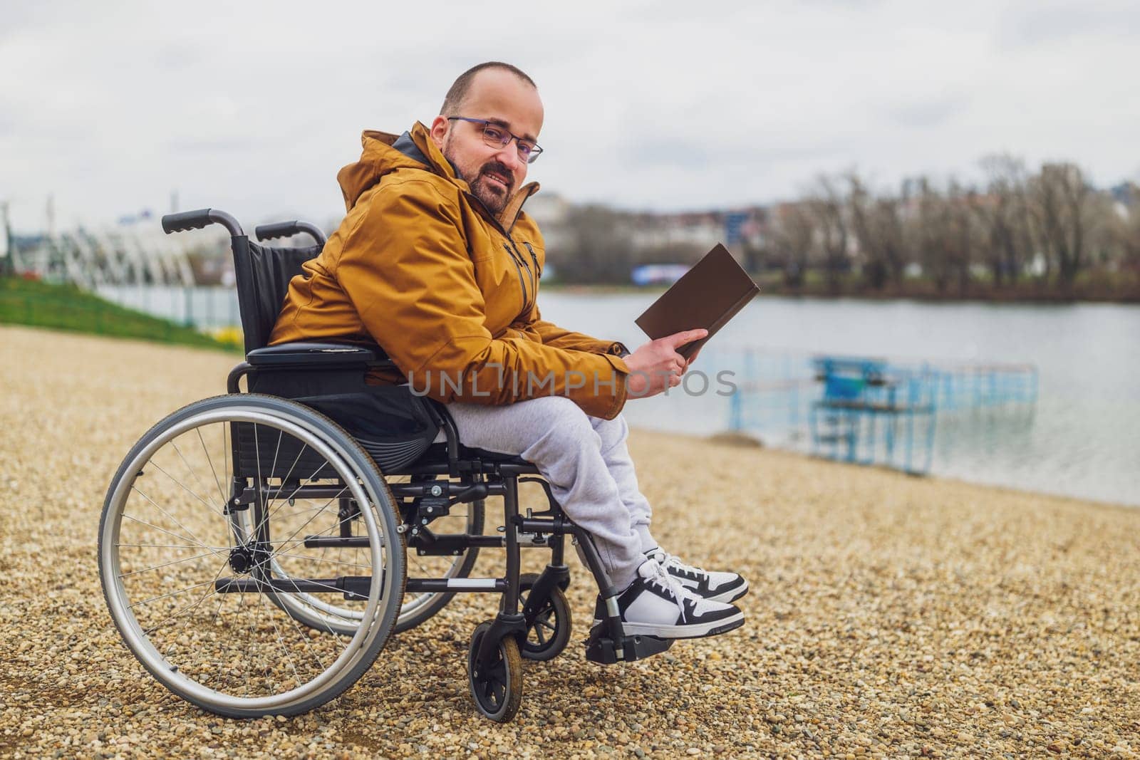 Paraplegic handicapped man in wheelchair is reading book by djoronimo