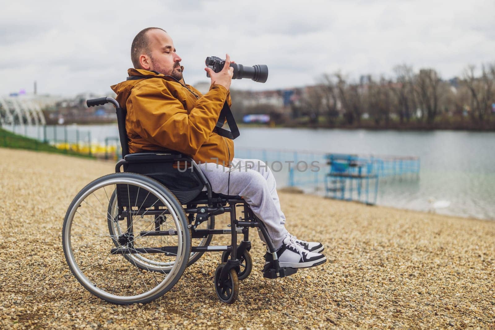Paraplegic handicapped man in wheelchair is photographing outdoor.
