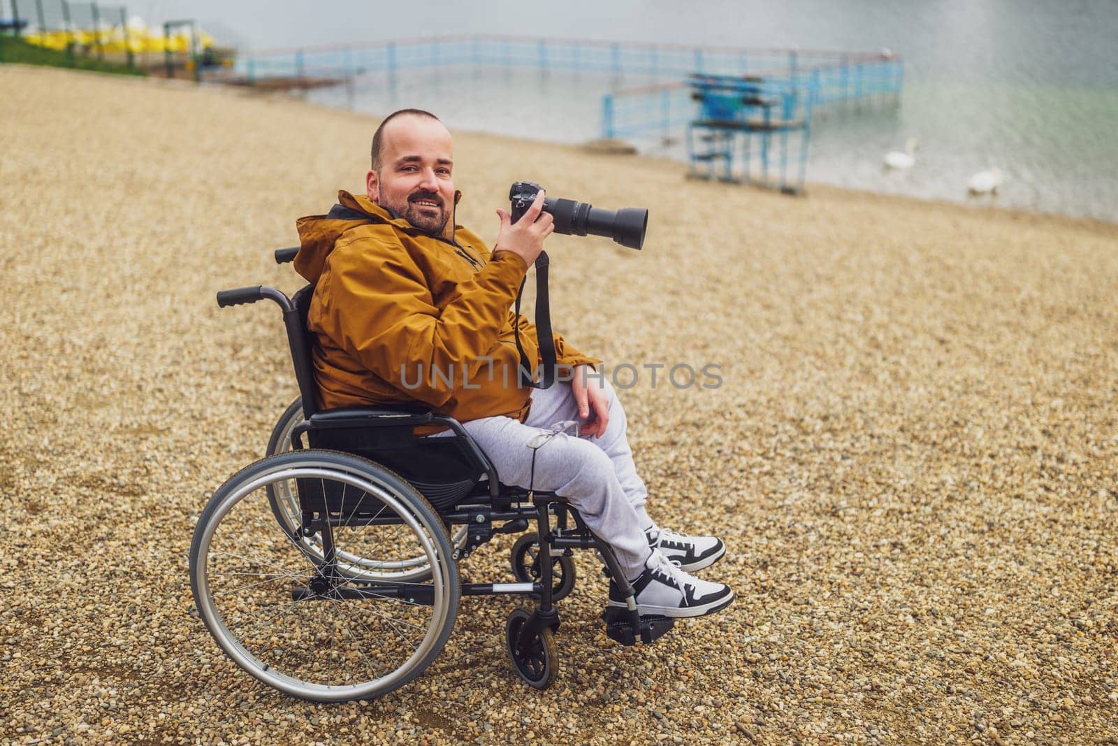 Paraplegic handicapped man in wheelchair is photographing outdoor.