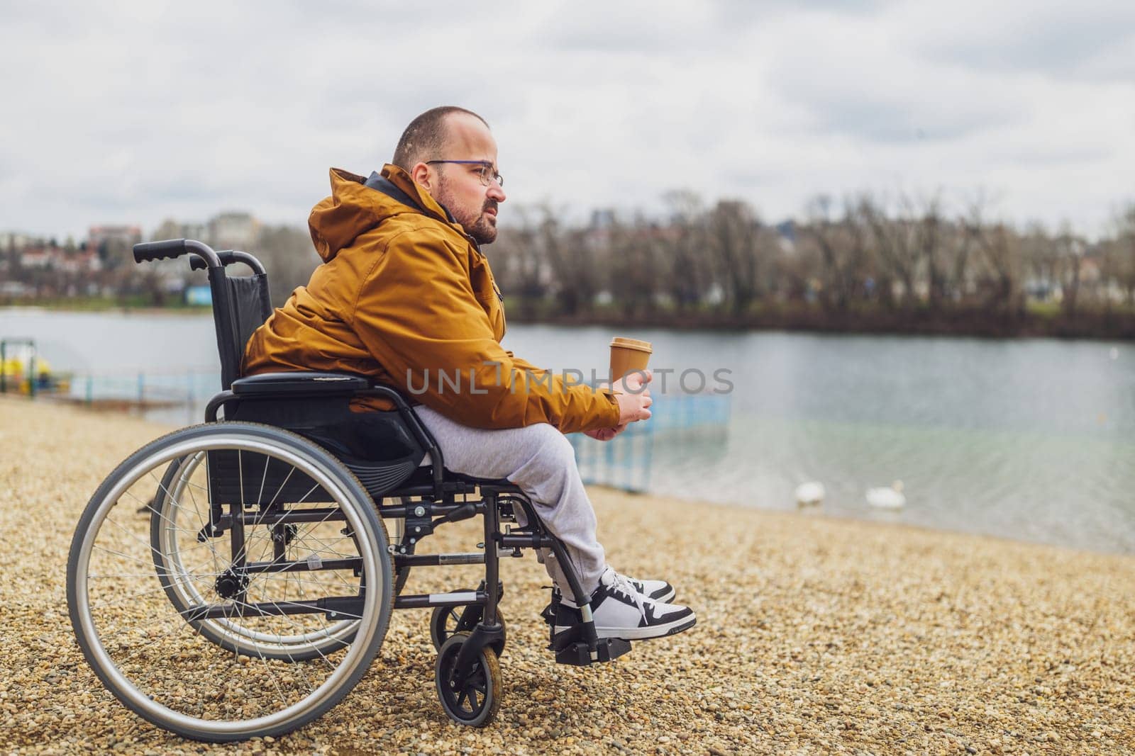 Paraplegic handicapped man in wheelchair is enjoying outdoor and drinking coffee.