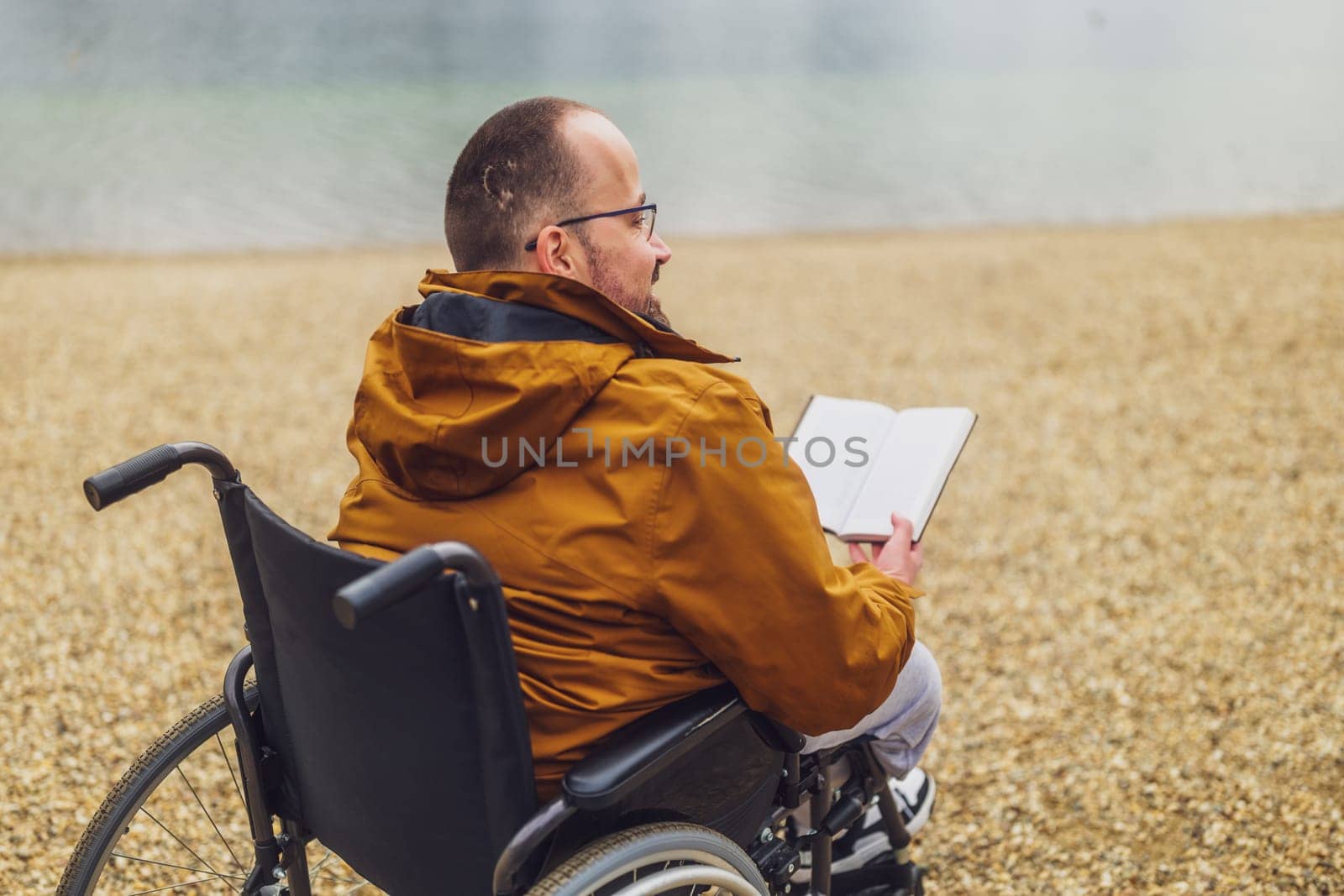 Paraplegic handicapped man in wheelchair is reading book by djoronimo