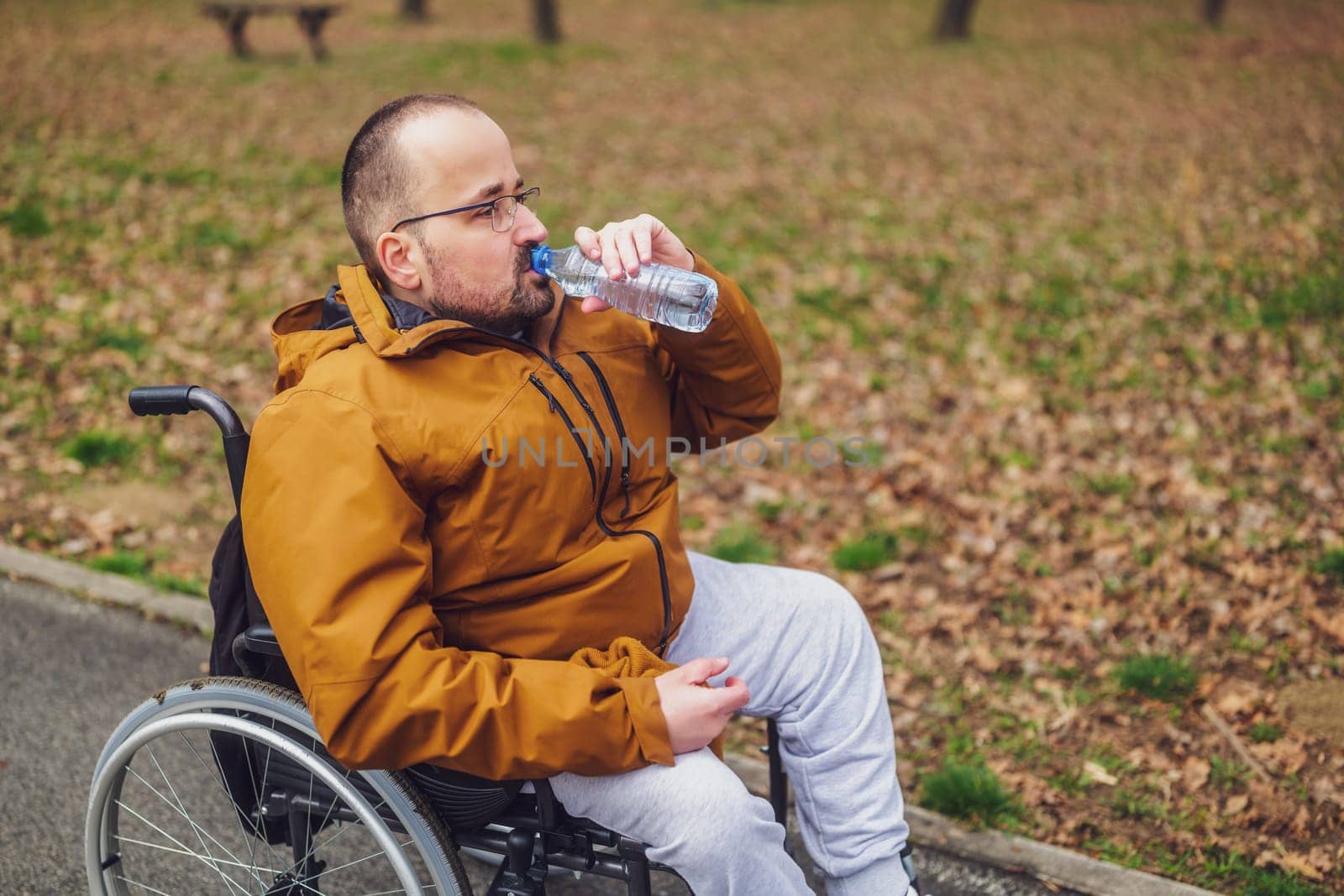 Paraplegic handicapped man in wheelchair is enjoying outdoor and drinking water by djoronimo
