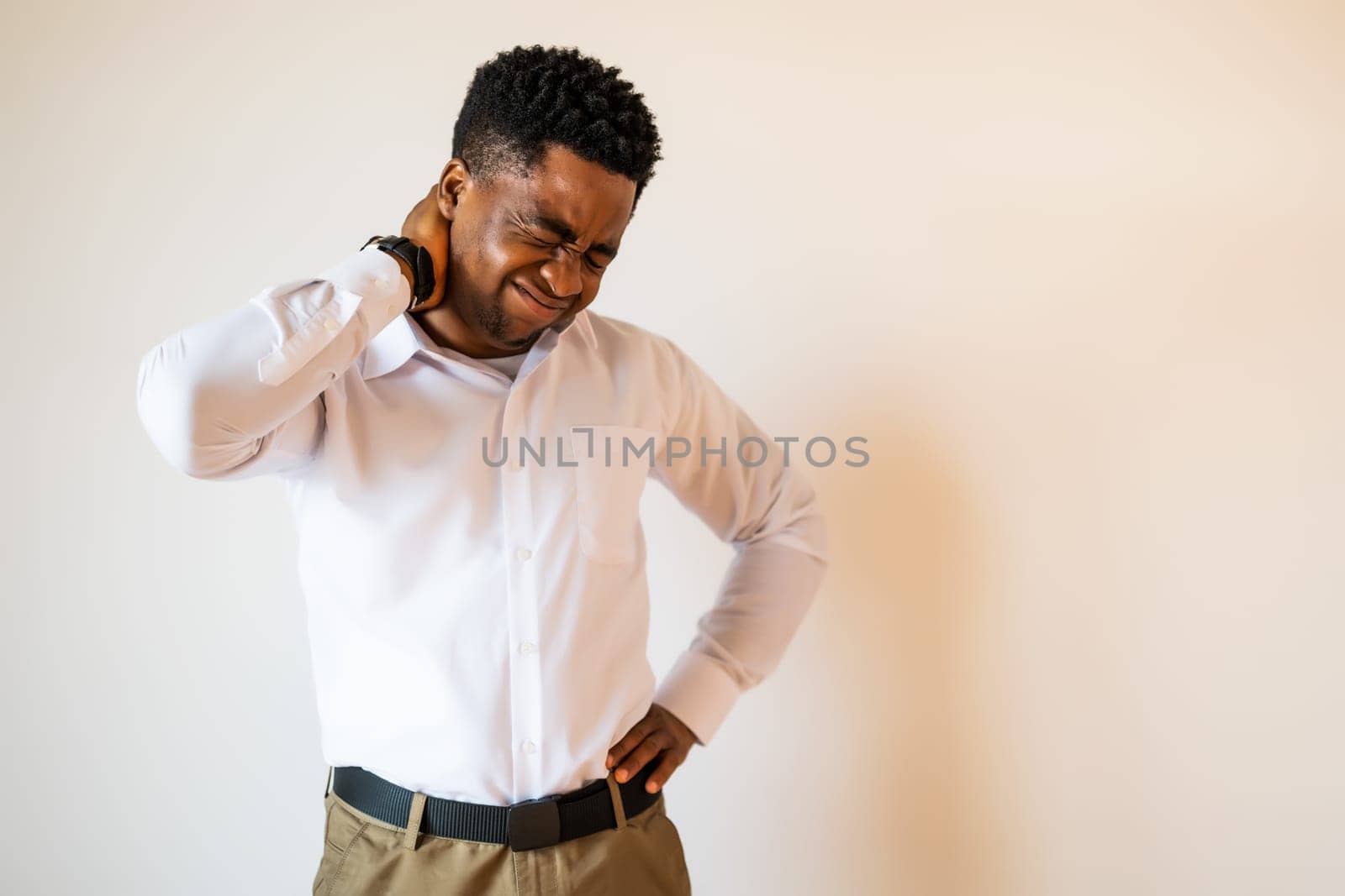Portrait of young businessman who is having pain in his neck. Copy space on image for your text or advert.