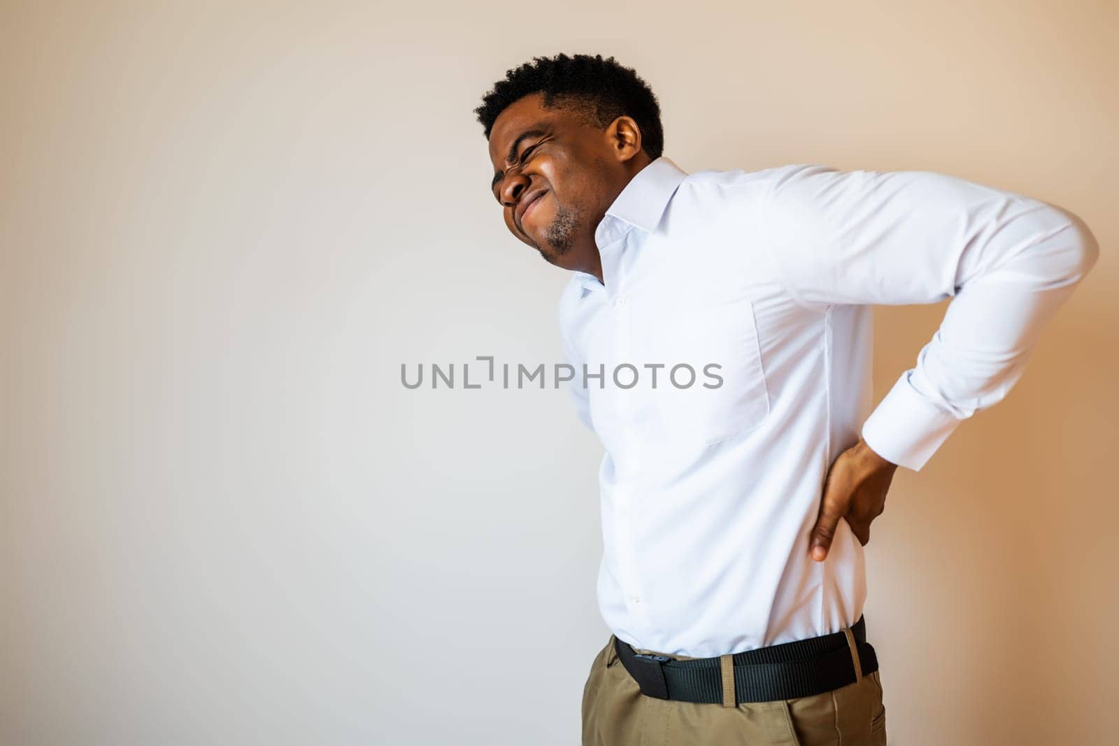 Portrait of young businessman who is having pain in his back. Copy space on image for your text or advert.