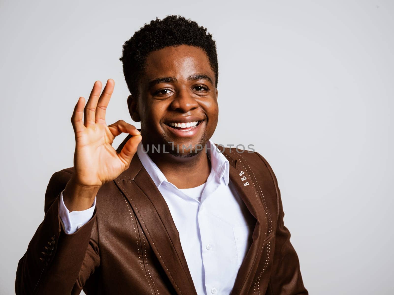 Portrait of happy businessman who is smiling and showing excellent sign. Copy space on image for your text or advert.