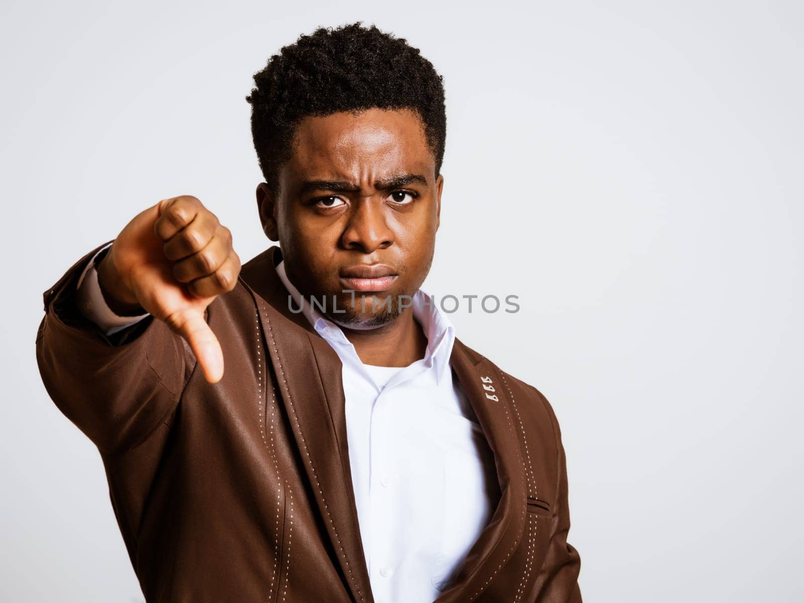 Portrait of young businessman who is angry and showing thumbs down.