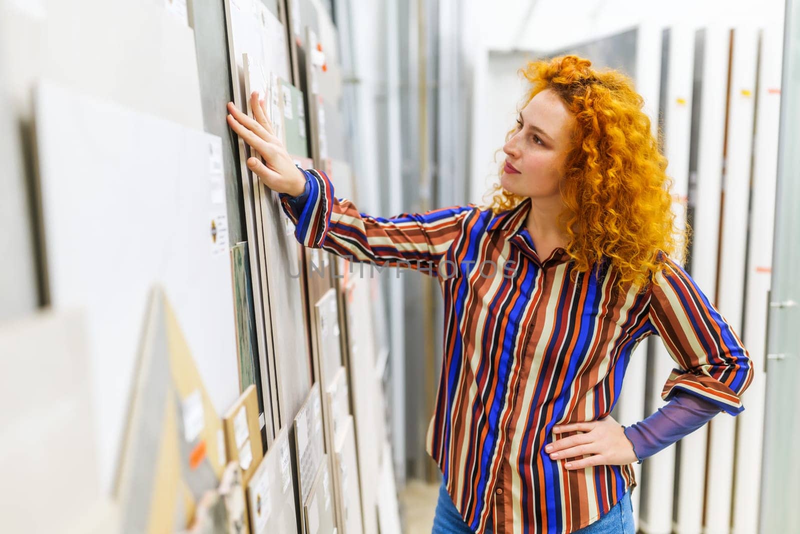 Portrait of buyer in bathroom store. Redhead woman is choosing tiles for her apartment.