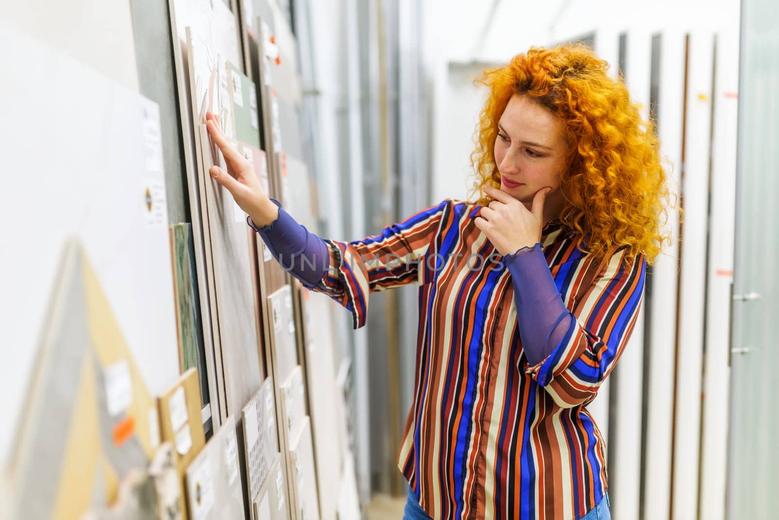 Portrait of buyer in bathroom store. Redhead woman is choosing tiles for her apartment.