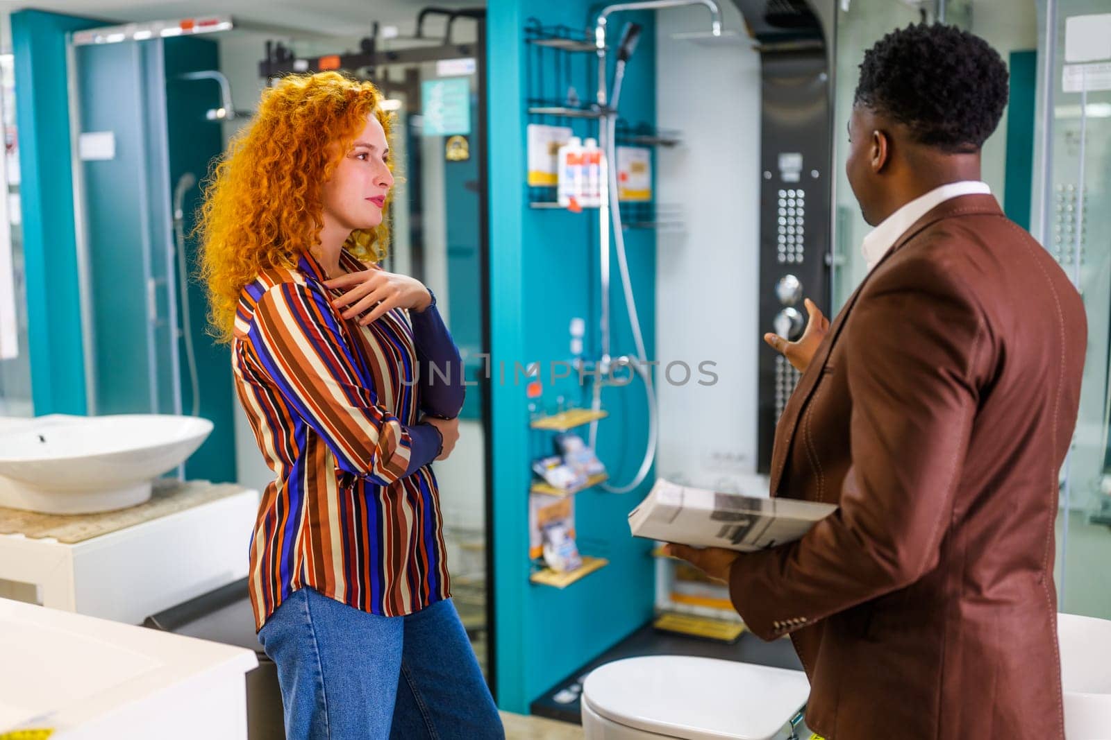 Businessman owns small business bath store. He is talking with a customer who is choosing the goods.