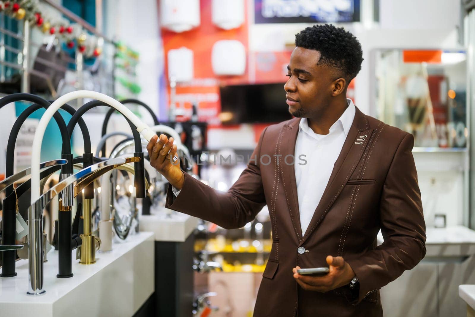 Portrait of buyer in bathroom store. Man is choosing faucet for his apartment.