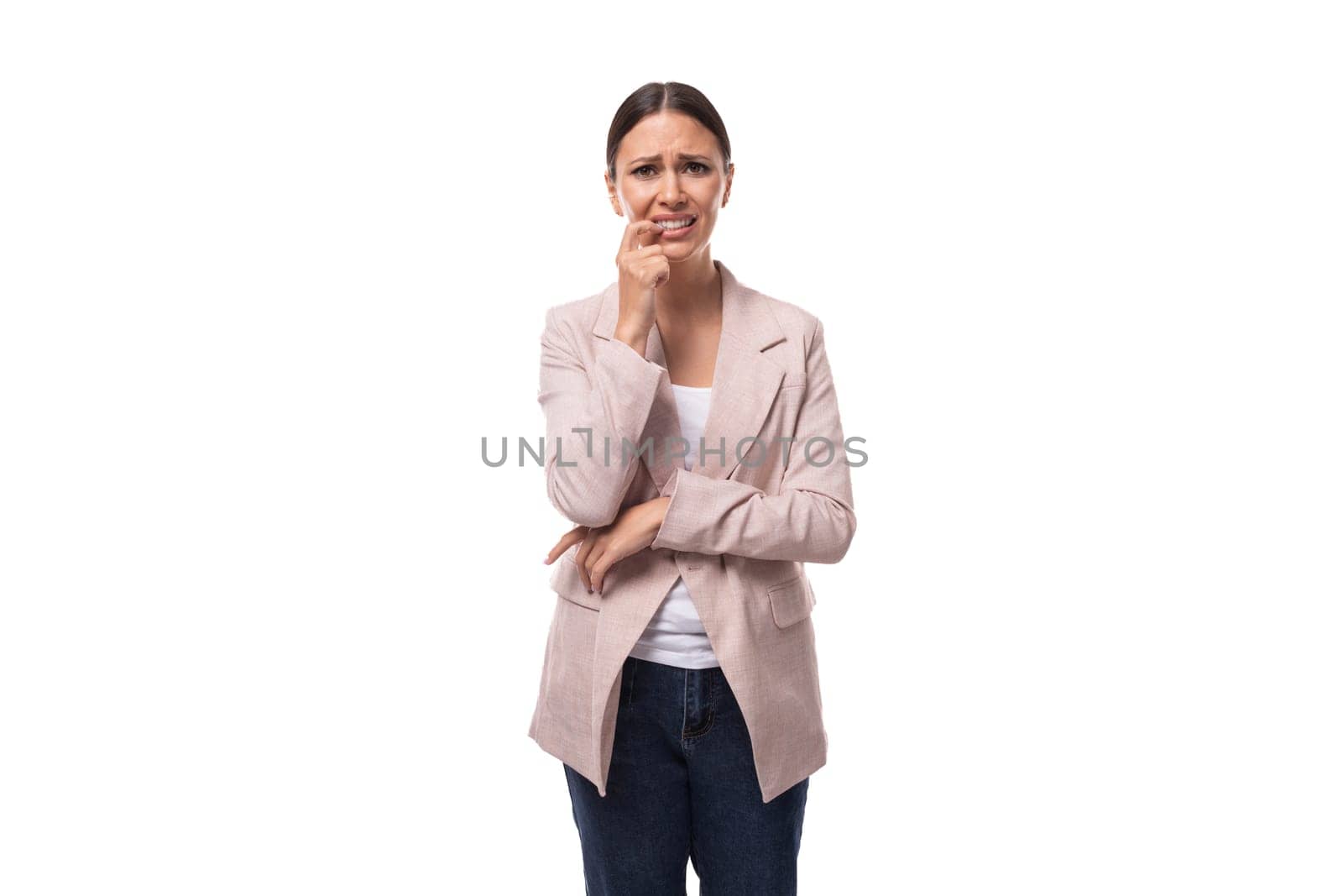 pleasant young woman with black hair in a jacket stands thoughtfully on a white background with copy space by TRMK