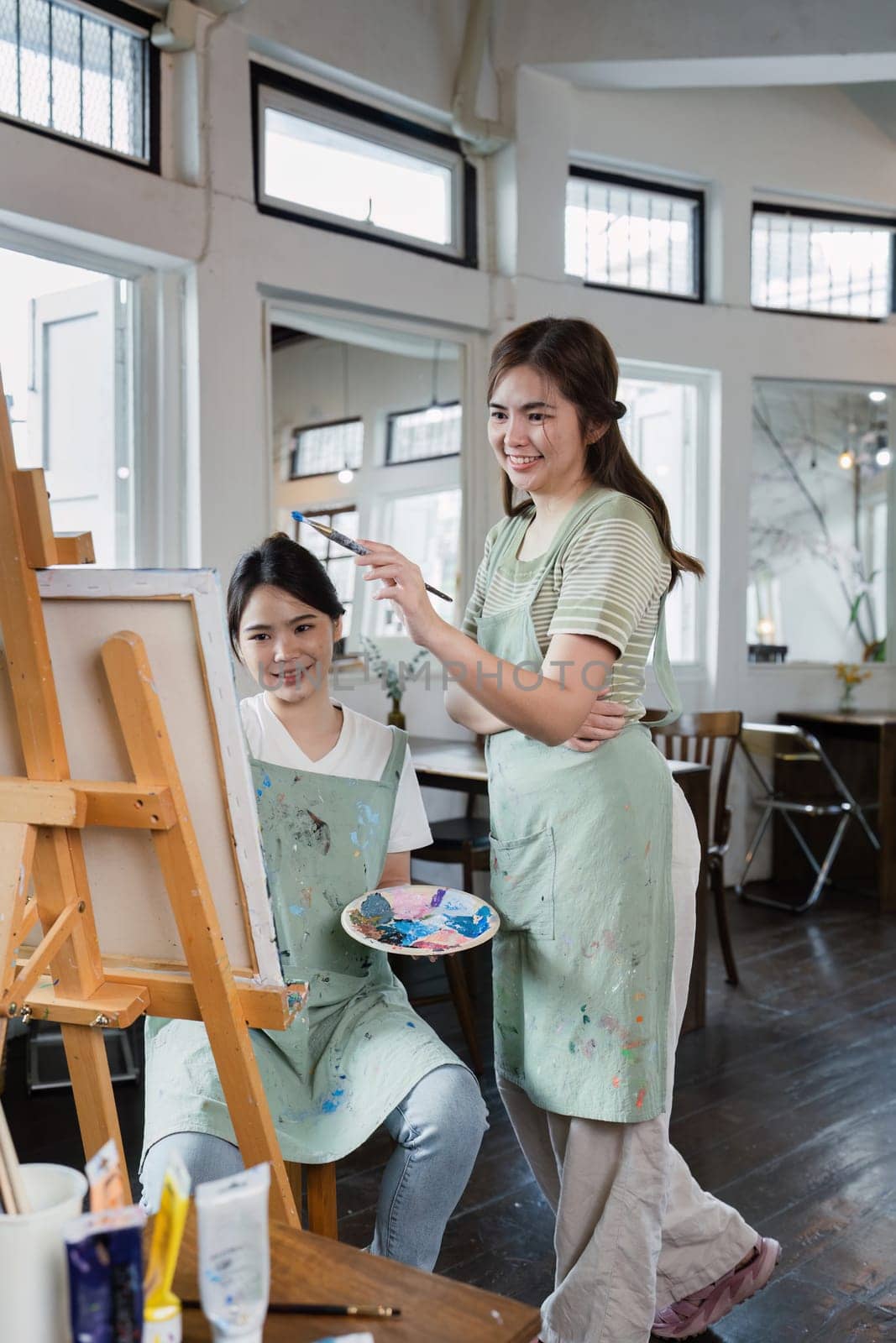 beautiful young woman artist working on painting something on a large canvas.