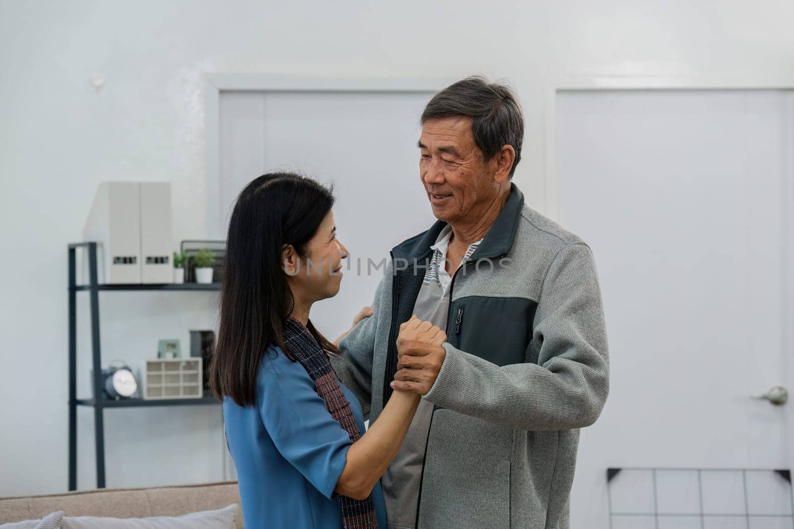 Happy cheerful middle aged mature couple family parent dancing together in the living room.