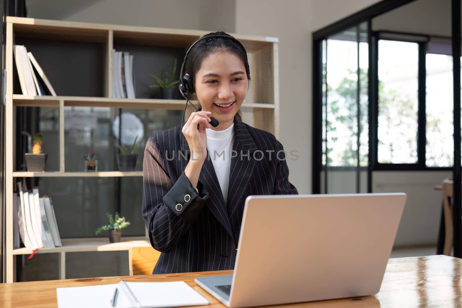 Call center agents wear headphones to talk to customers. Provide consultation via online channels on laptops by wichayada