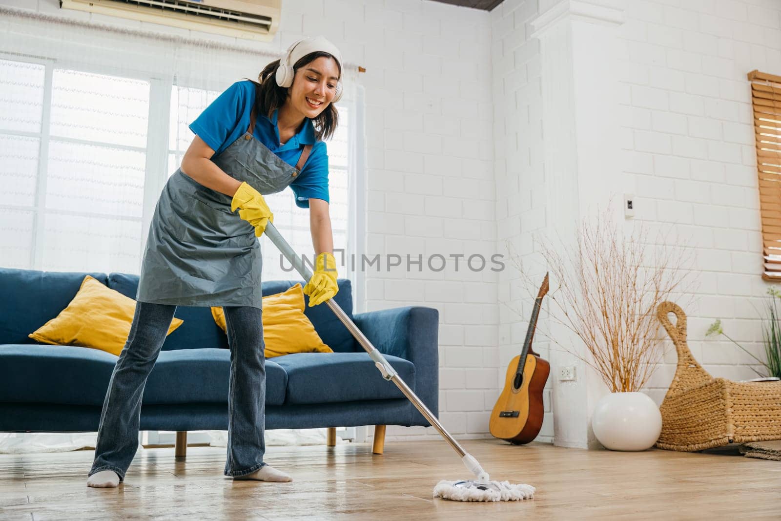 Asian teenager lively cleanup, maid listens dances sings using headphones. Joyful occupation with music excitement. Modern cleaning tech-driven fun. Give me melody, Happy and Fun During Cleaning