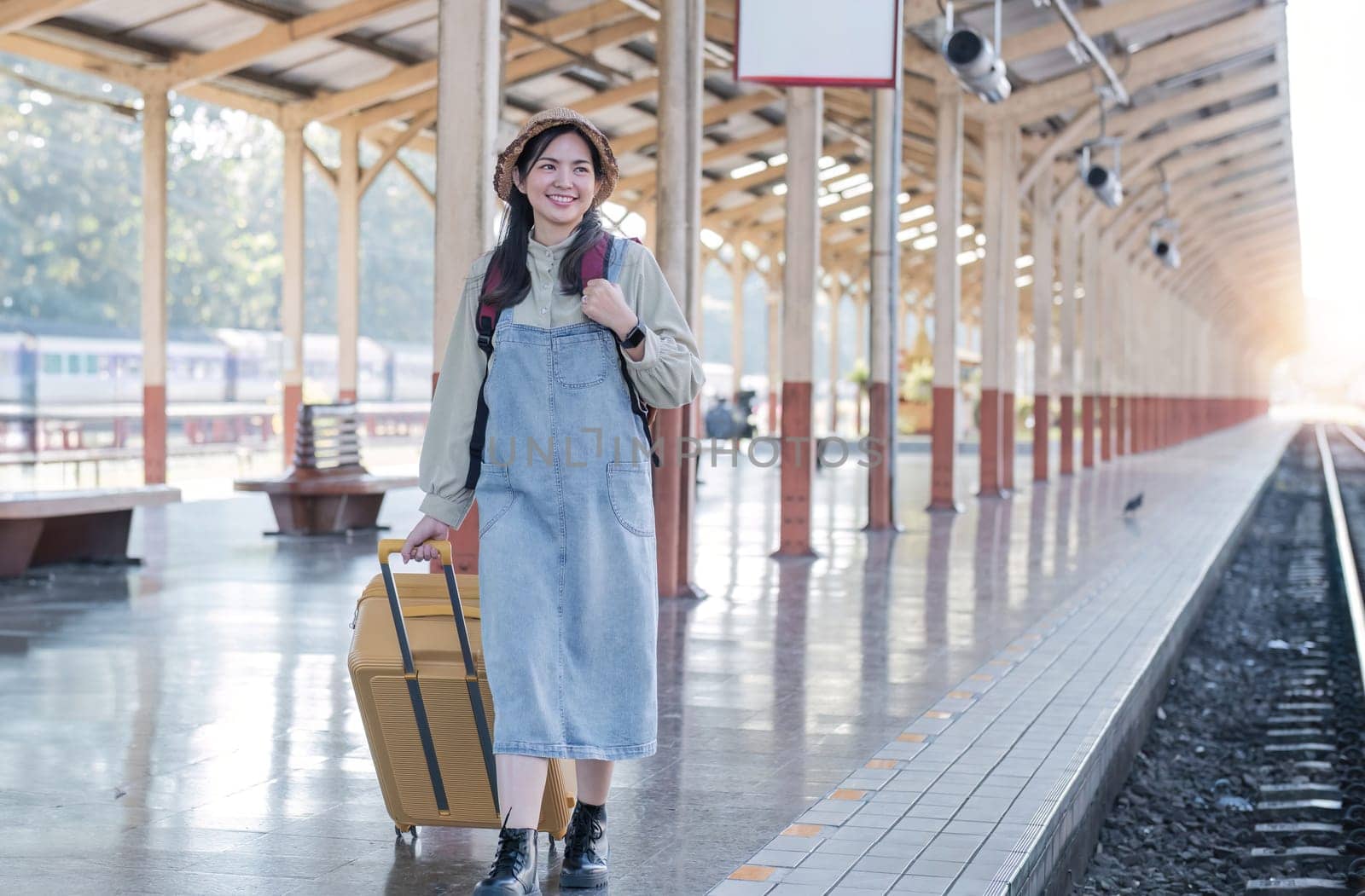 Young Asian woman in modern train station Female backpacker passenger waiting for train at train station to go on holiday. by wichayada