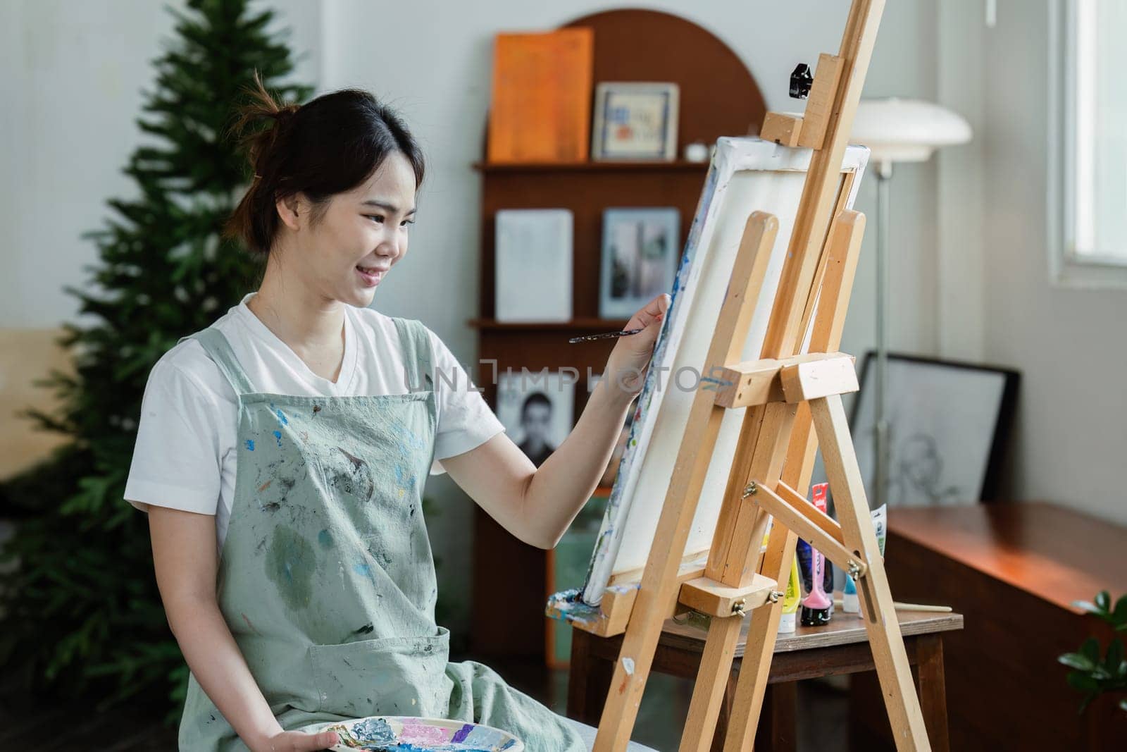 beautiful young woman artist working on painting something on a large canvas by itchaznong