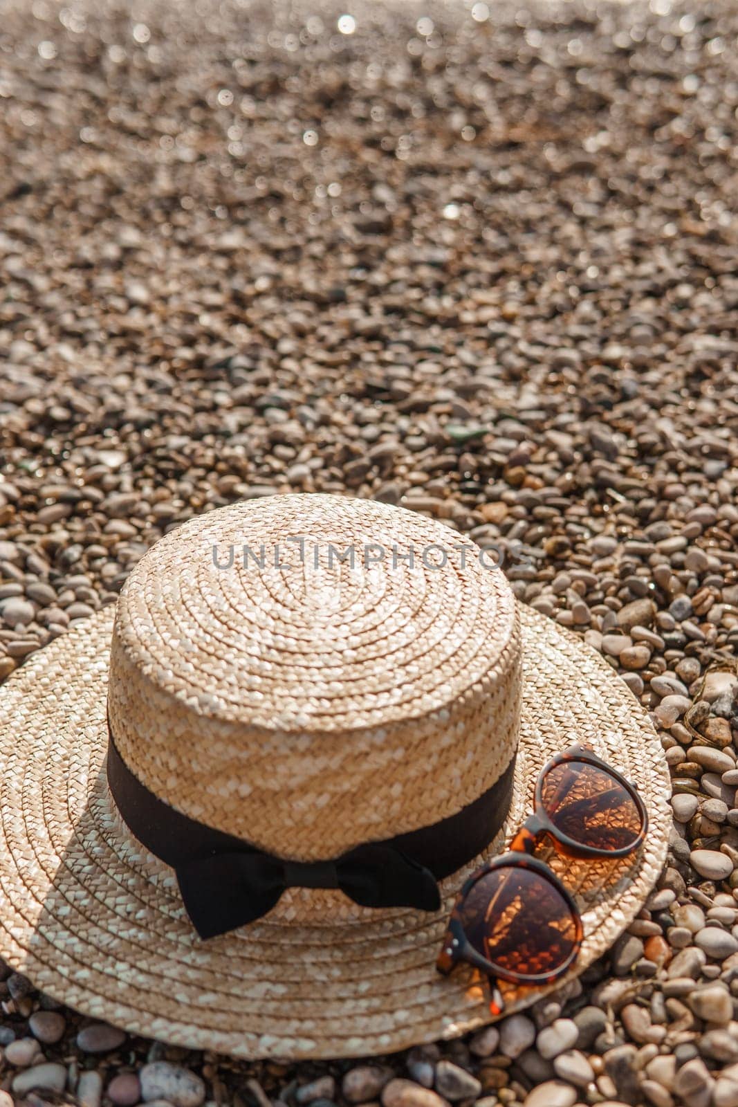 A straw hat and sunglasses on the beach. Pebbles on the seashore, close-up. The natural background. by Annu1tochka