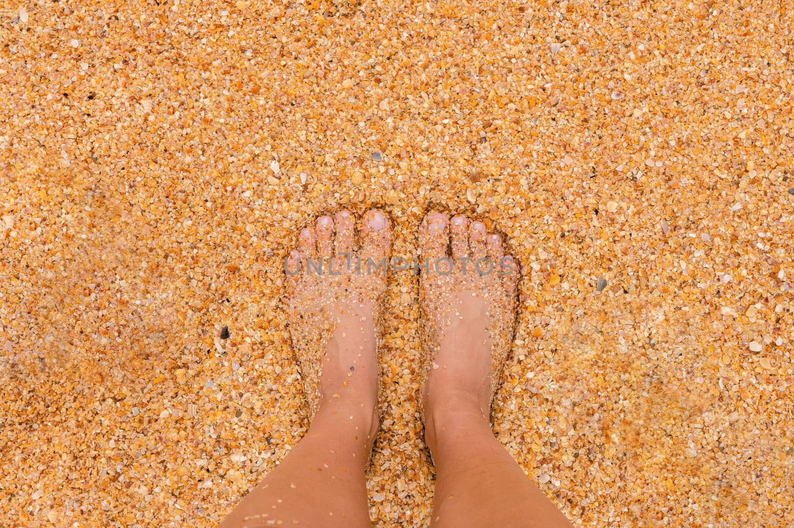 A young woman stands barefoot on the sand on a sunny summer day. Part of the body. Shot point of view. Blank space for inspirational, happy text, quote or saying. by yanik88