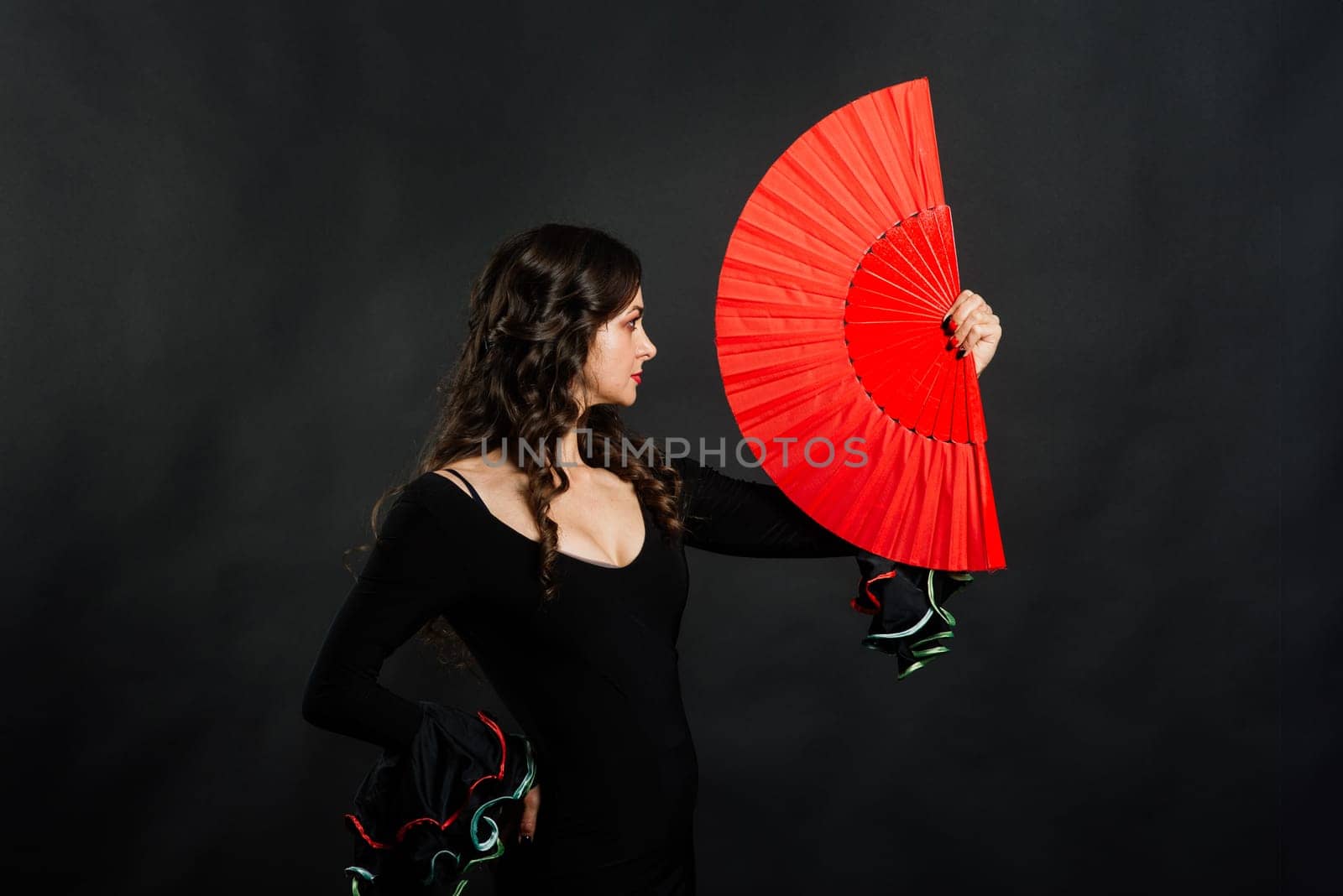 Portrait of beautiful young woman dancing flamenco with fan in studio