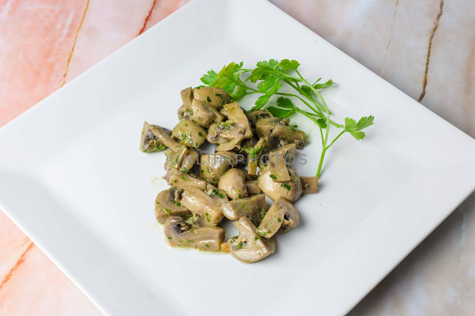 Herb-marinated mushrooms with parsley on a square white plate, typical food, typical mediterranean mallorcan cuisine typical from balearic islands mallorca, spain,