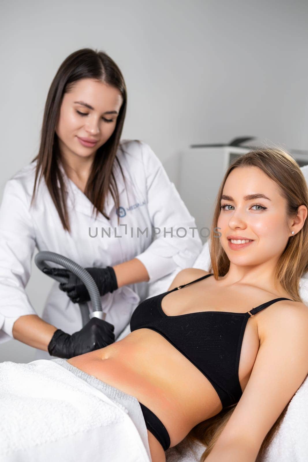 Beautiful beautician and patient during an ultrasound lifting procedure targeted at the womans belly