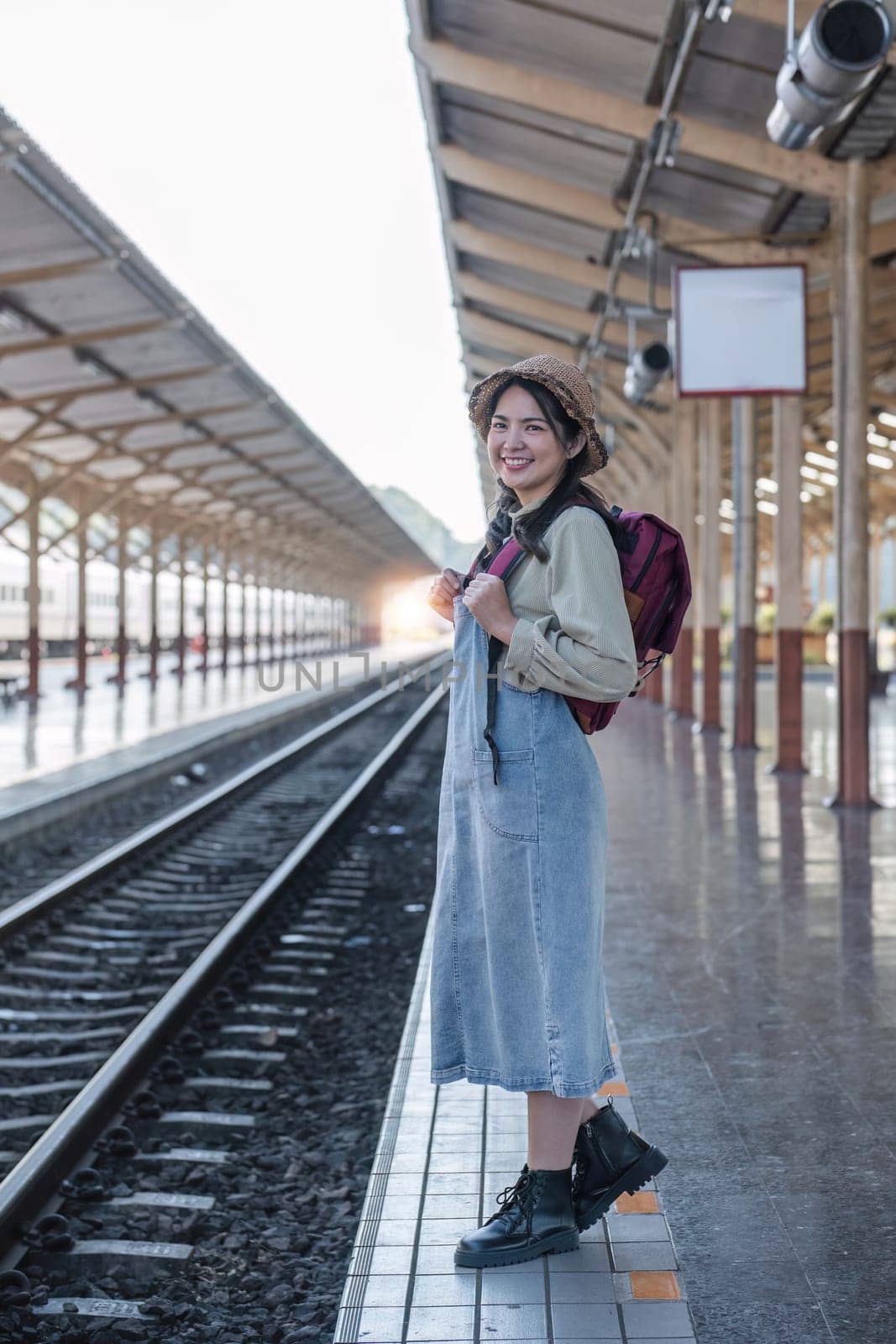 Young Asian woman in modern train station Female backpacker passenger waiting for train at train station to go on holiday..