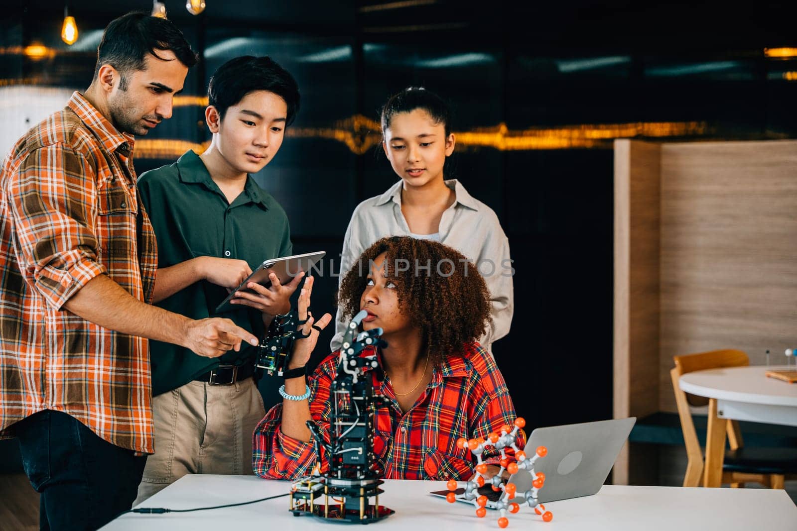 In a classroom at school students and teacher study and experiment on a robotic arm. Encouraging innovation teamwork and practical learning in education. Robot hand. Innovation and technology concept by Sorapop