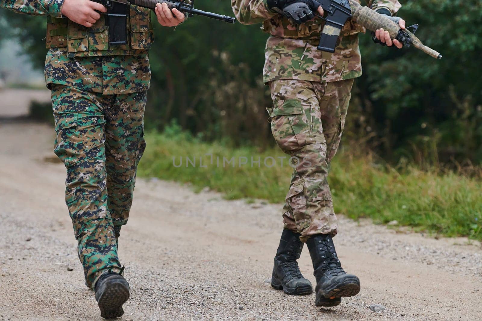 Close up photo, the resilient legs of elite soldiers, clad in camouflage boots, stride purposefully along a hazardous forest path as they embark on a high-stakes military mission.