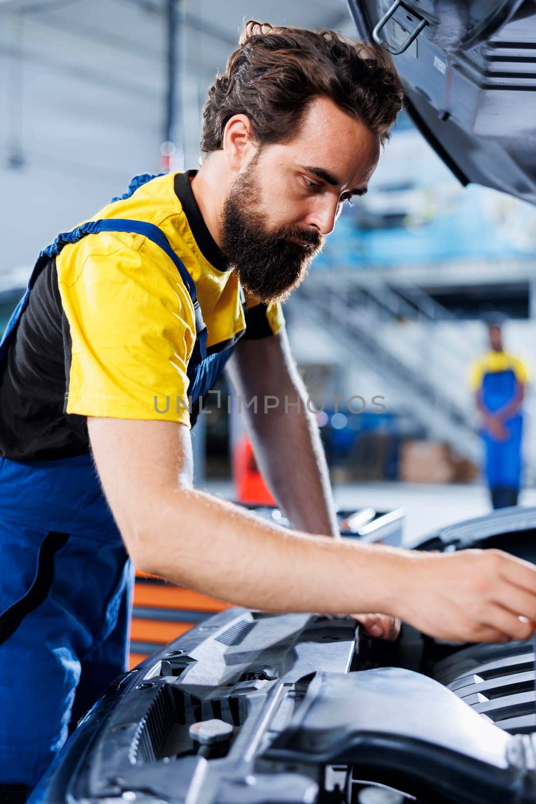 Car service mechanic expertly examines engine using advanced mechanical tools, ensuring optimal automotive performance and safety. Seasoned garage expert conducts annual vehicle checkup