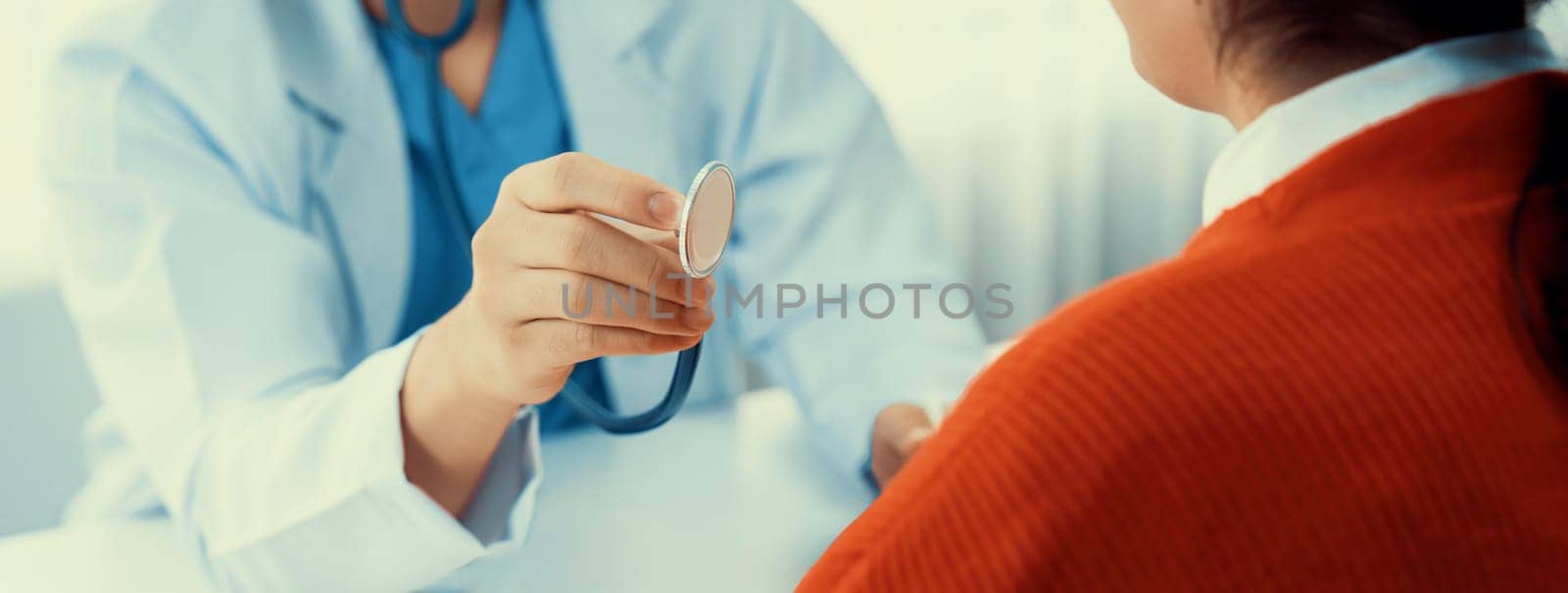 Patient attend doctor's appointment at clinic or hospital office. Doctor examining and diagnosis symptoms while checking the patient's pulse with stethoscope. Panorama Rigid