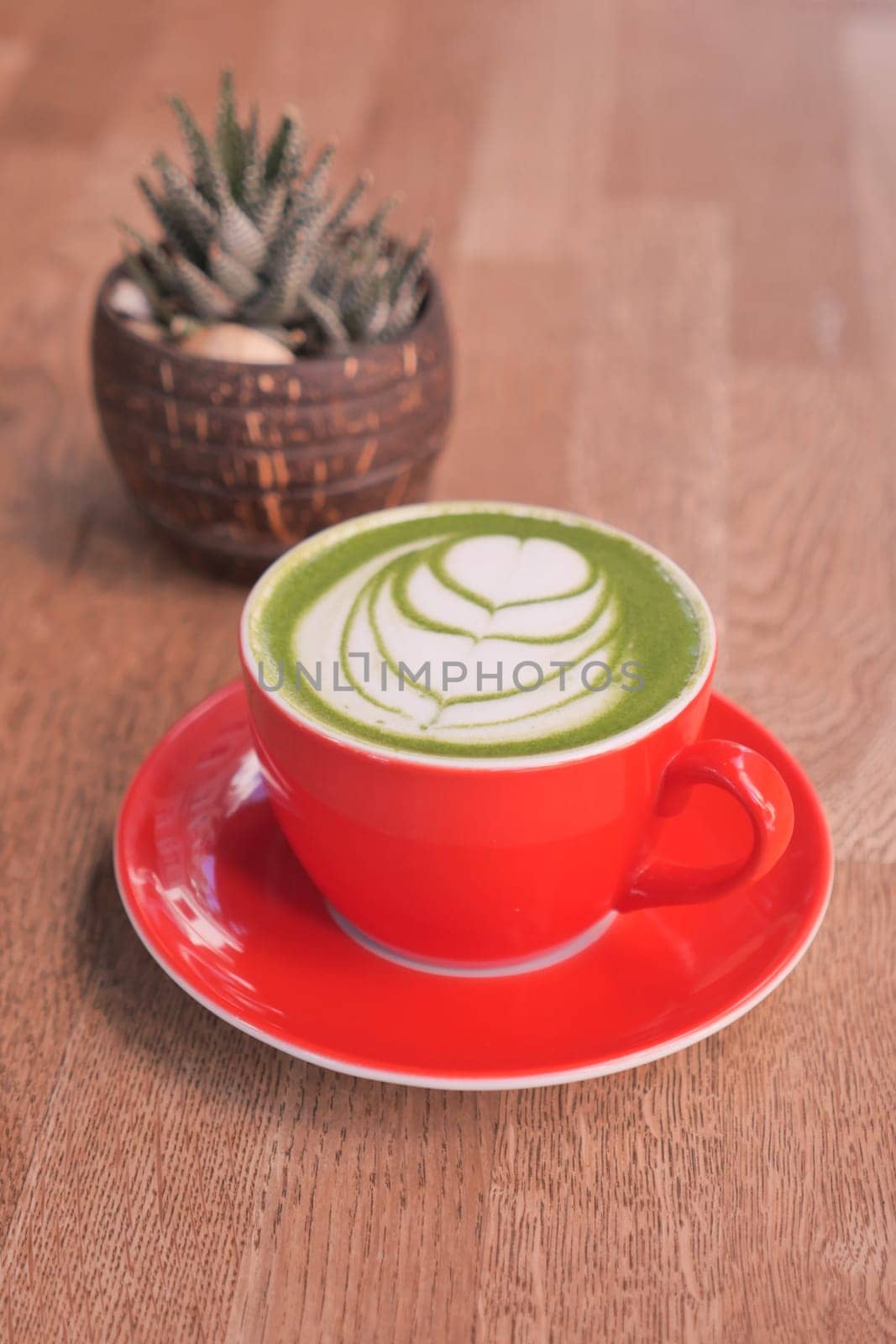 matcha latte in a red color cup on table by towfiq007