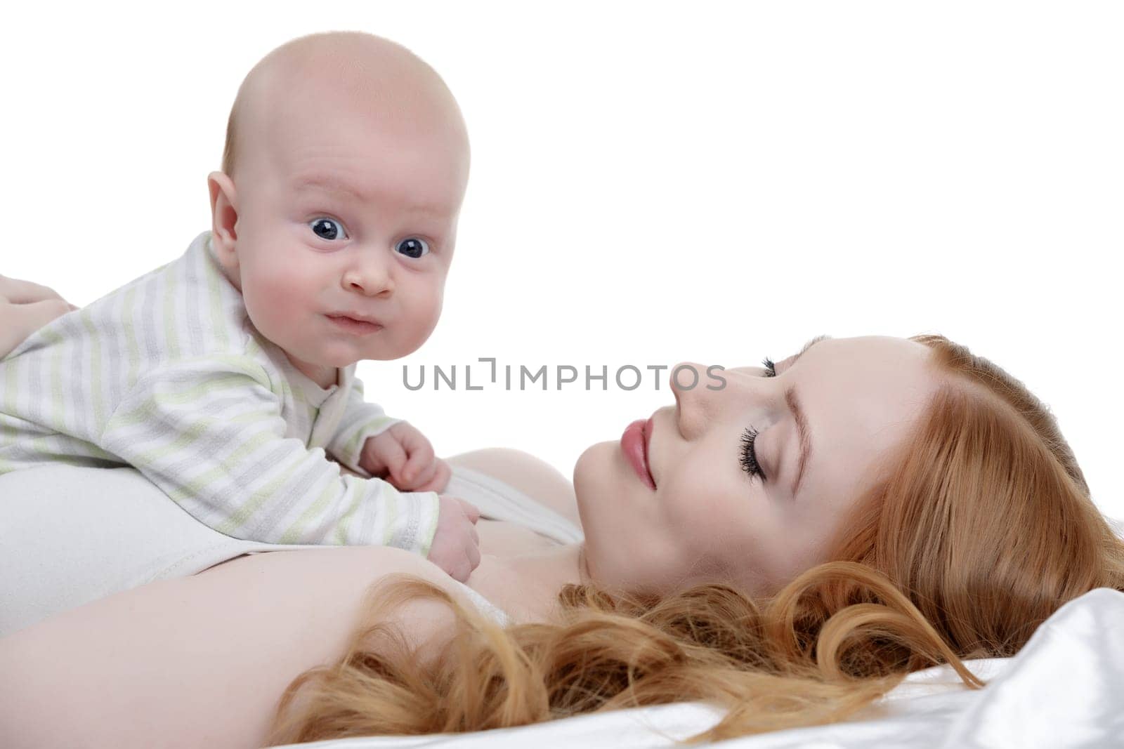 Toddler posing at camera while lying on mother's breast