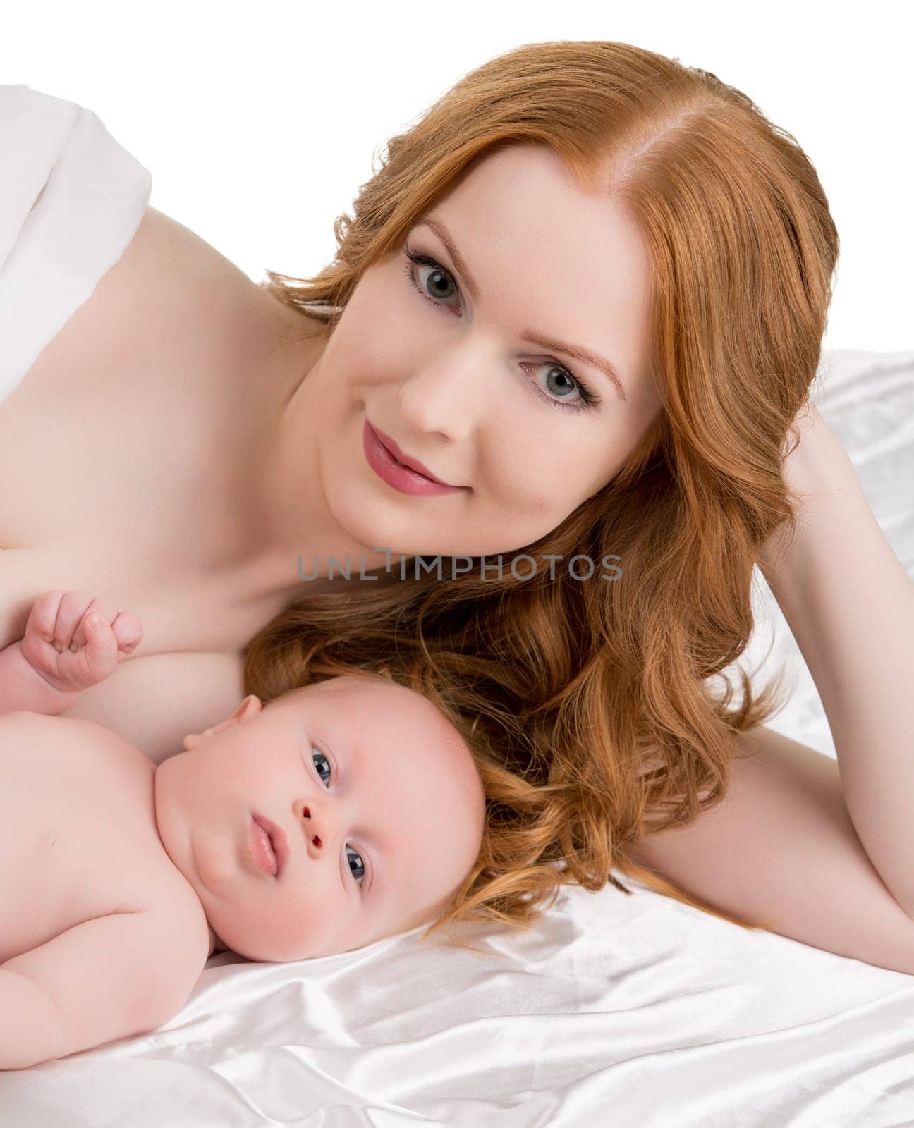 Beautiful red-haired woman and her adorable baby posing at camera