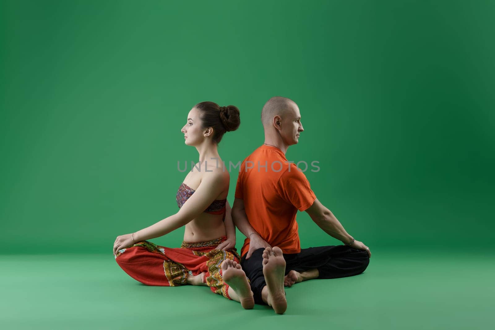 Yoga. Man and woman sitting backs to each other by rivertime