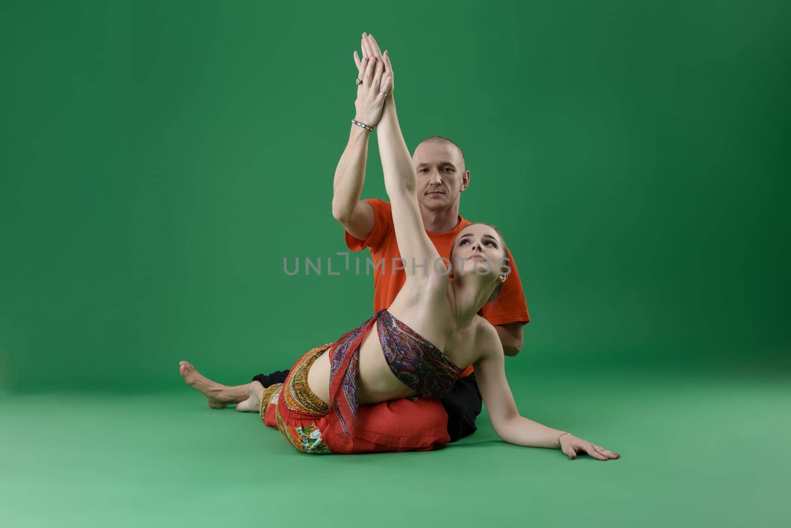 Yoga. Studio photo of instructor helps woman to perform asana