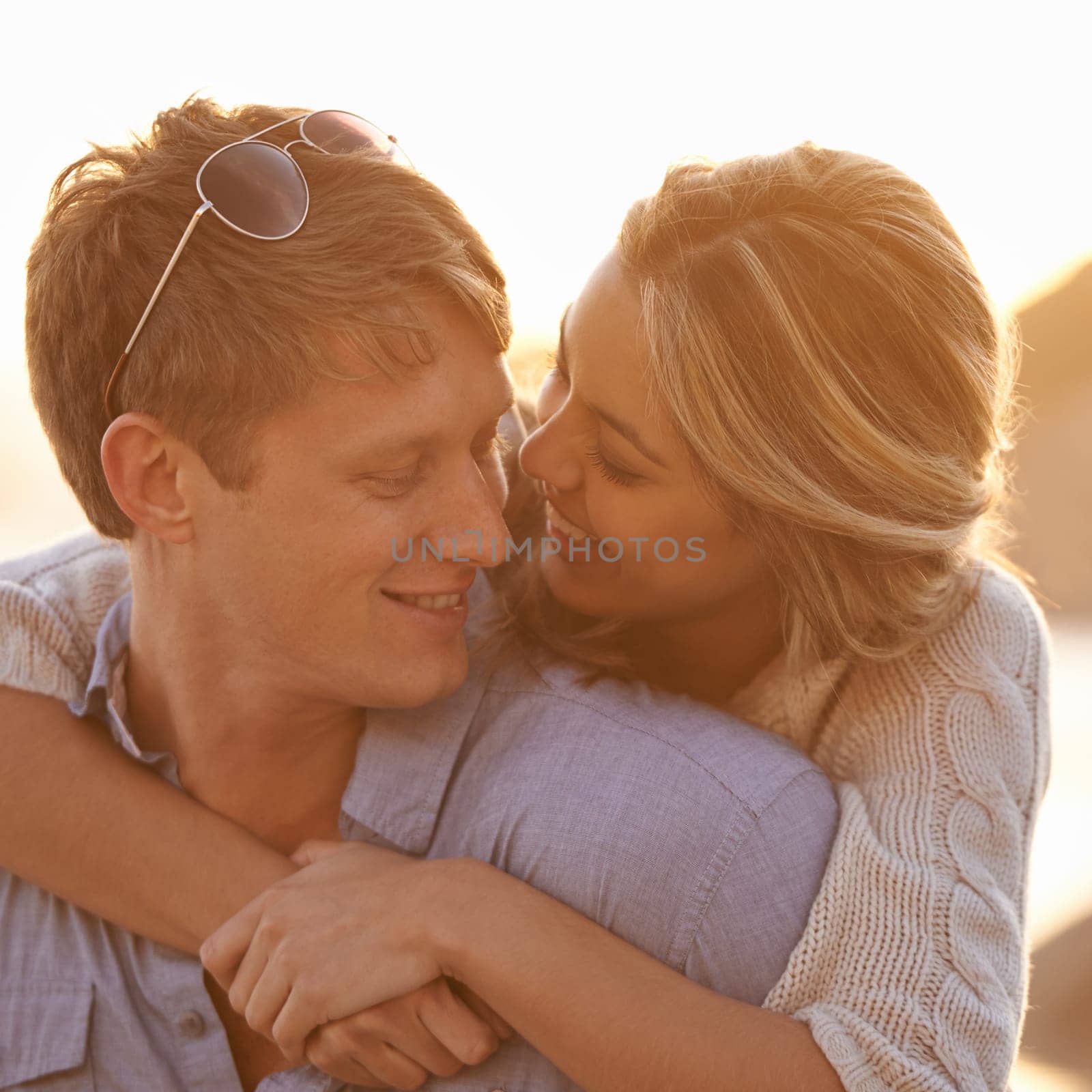 Couple, sunset and hug for love by water, ocean waves and peace for romance in relationship. Happy people, looking and security in marriage, embrace and travel on vacation or holiday for outdoor date.