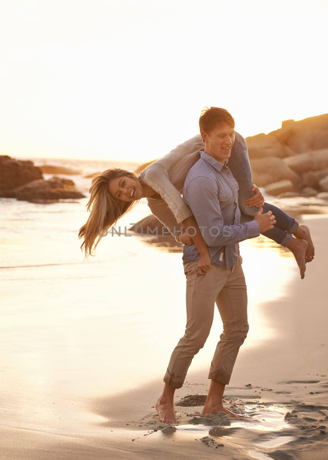 Beach, man and woman playful in sand together for romantic date, travel or holiday on island. Ocean, vacation and couple laughing in waves for tropical adventure for honeymoon, anniversary and sunset by YuriArcurs