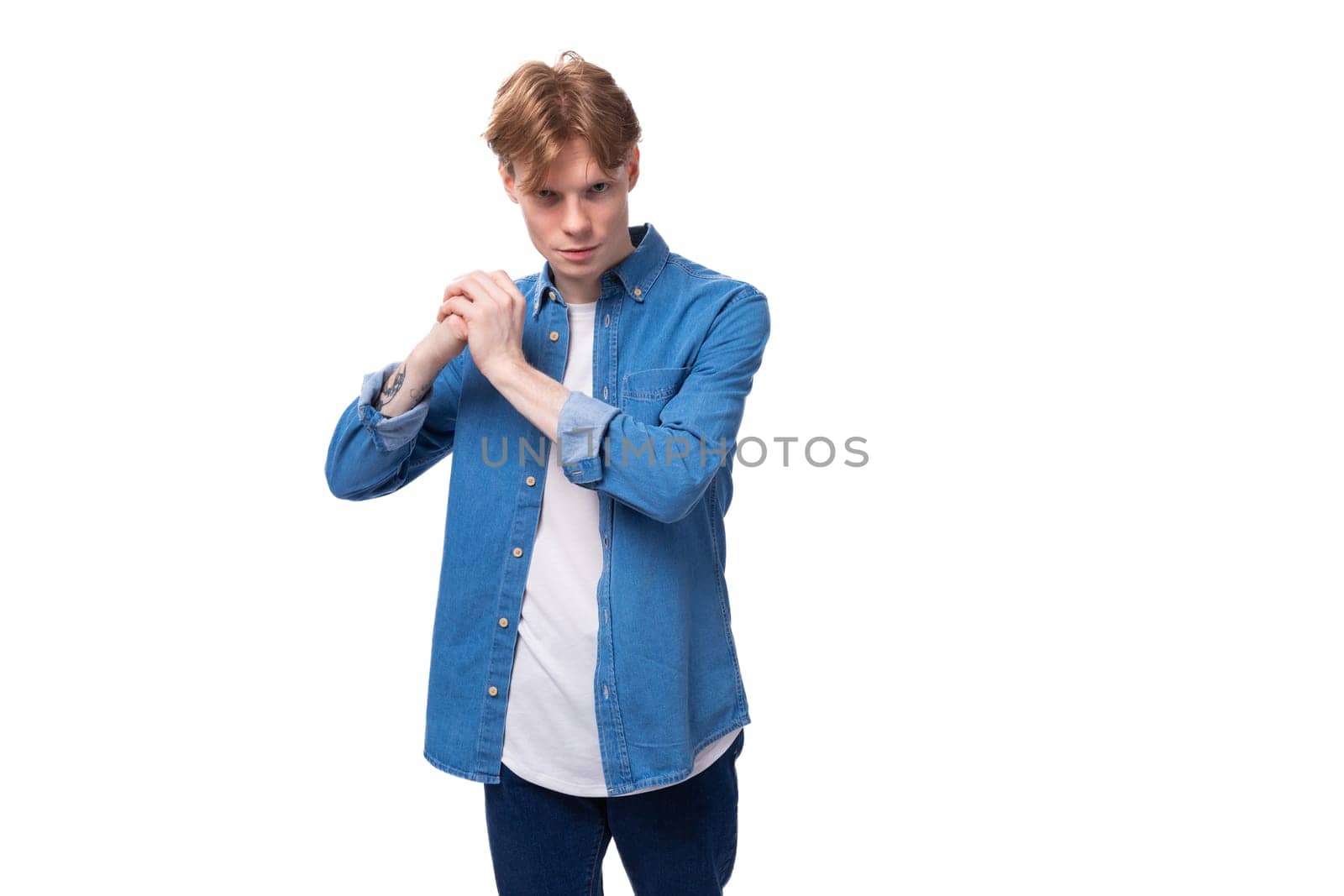 young red-haired guy in a blue denim shirt on a background with copy space.