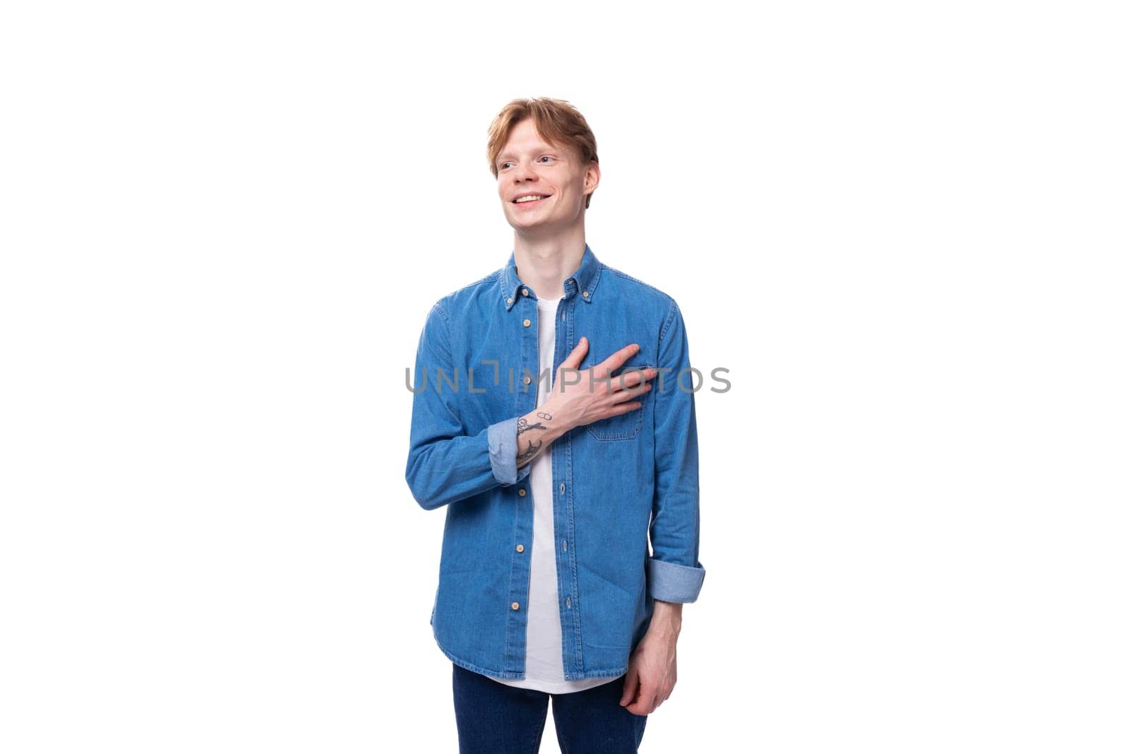 young caucasian man with red hair dressed in a blue shirt on a white background with copy space by TRMK