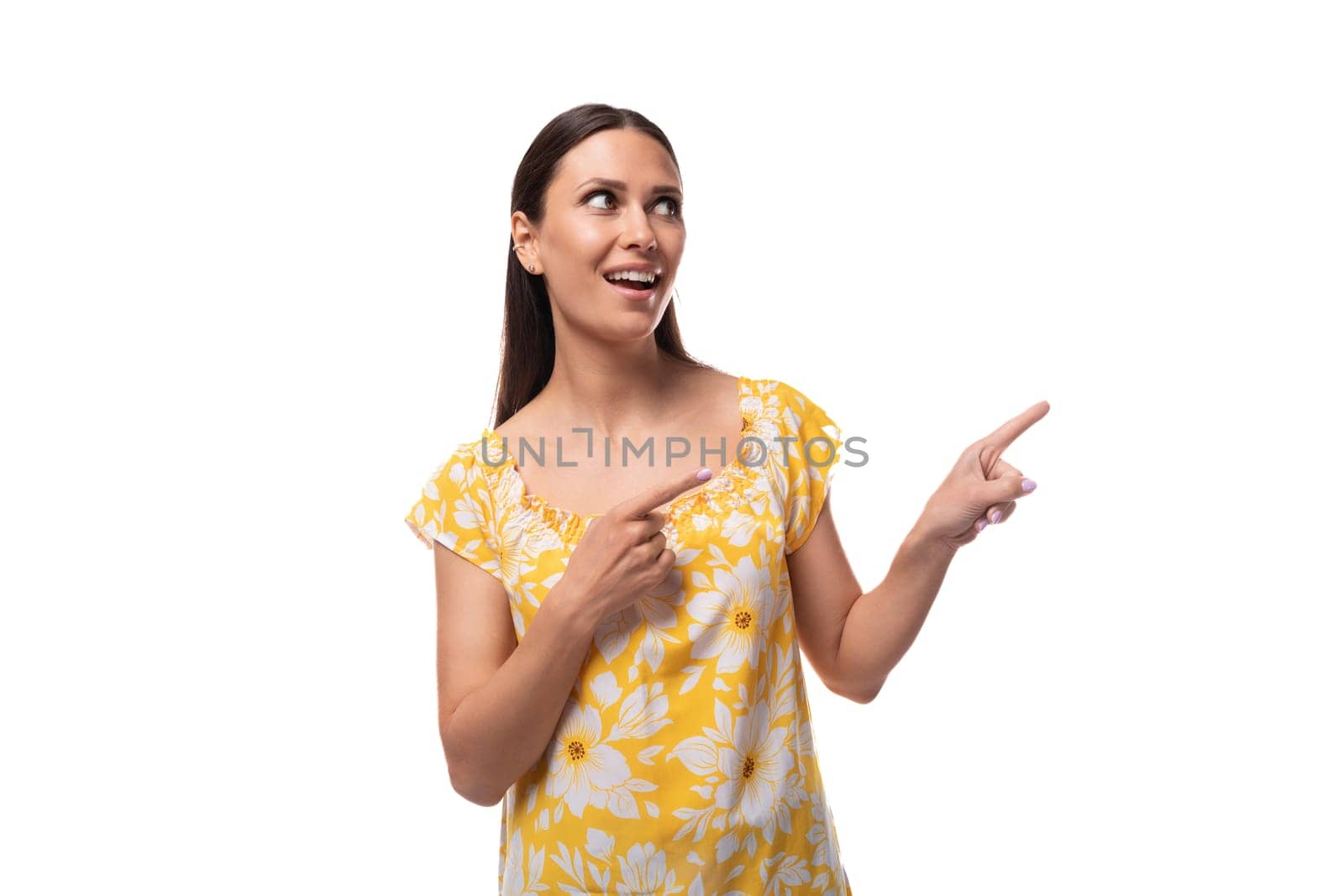 brunette young woman dressed in a summer yellow outfit points her finger to the side by TRMK