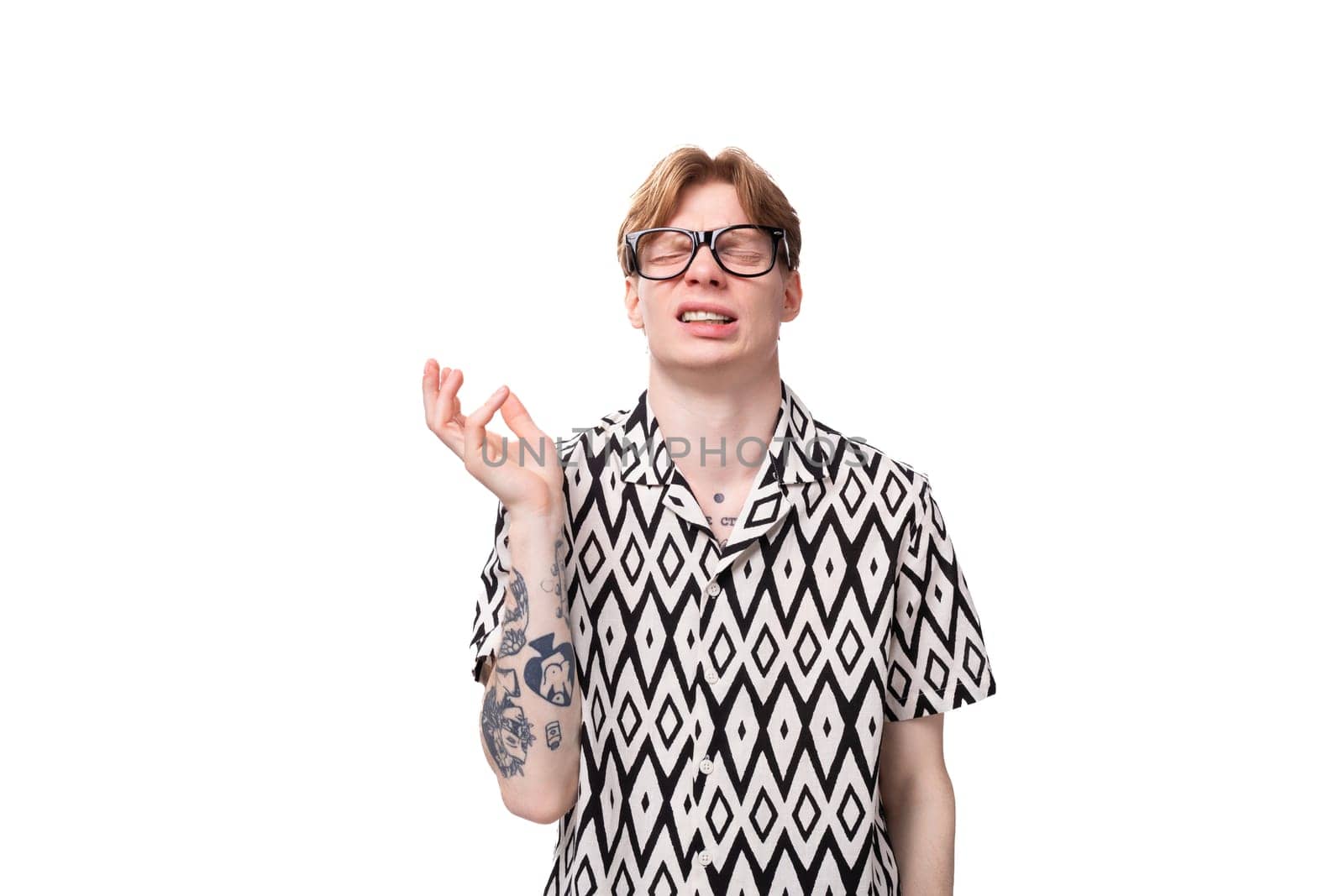 a young man with golden hair and a tattoo on his arms wears glasses for image and a black and white shirt by TRMK