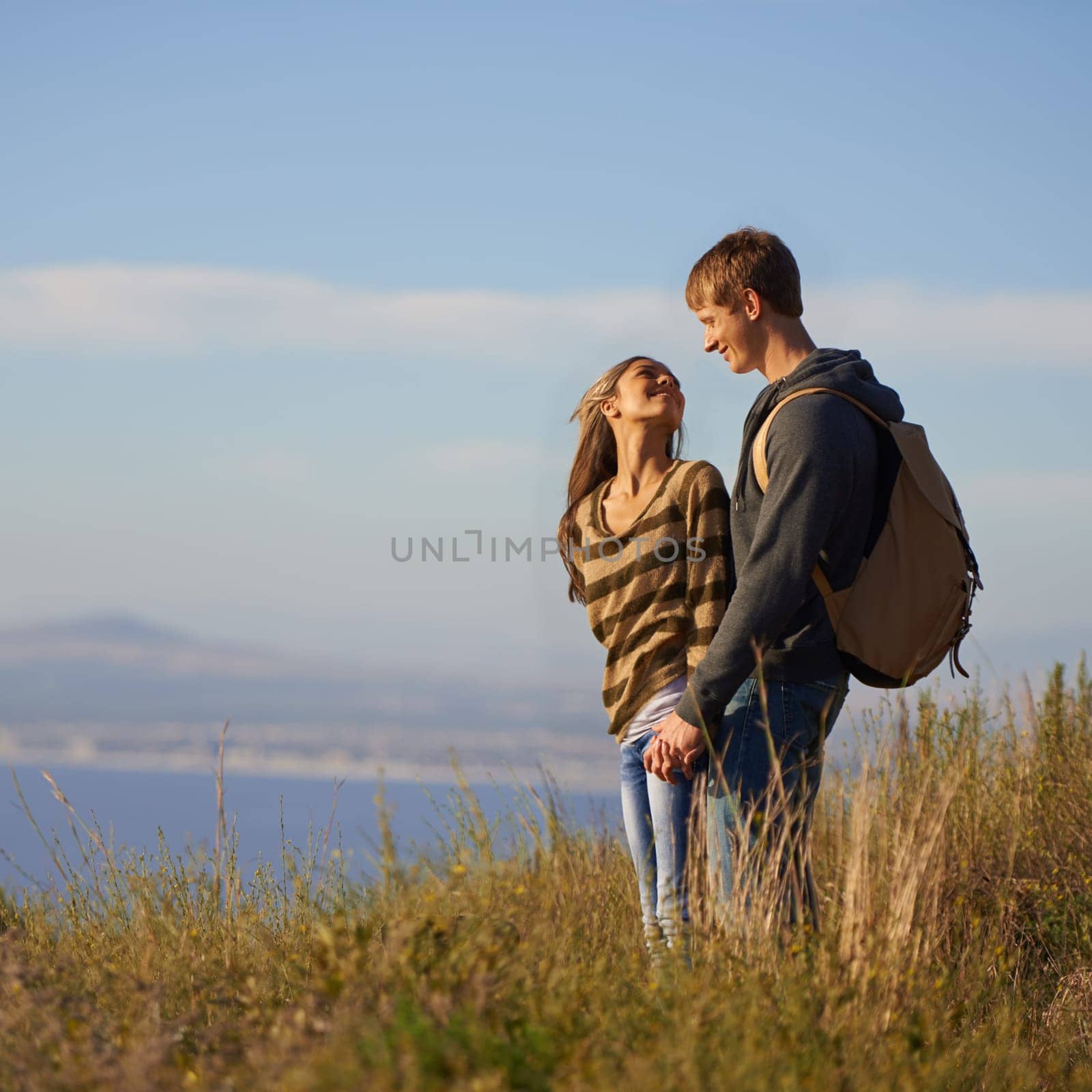 Smile, hiking and couple holding hands in nature for holiday, travel or adventure outdoor together. Love, man and happy woman trekking in the countryside for bonding on vacation, journey and mockup.