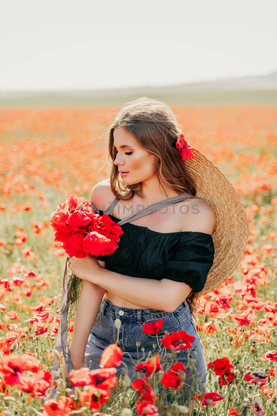 Woman poppies field. portrait of a happy woman with long hair in a poppy field and enjoying the beauty of nature in a warm summer day