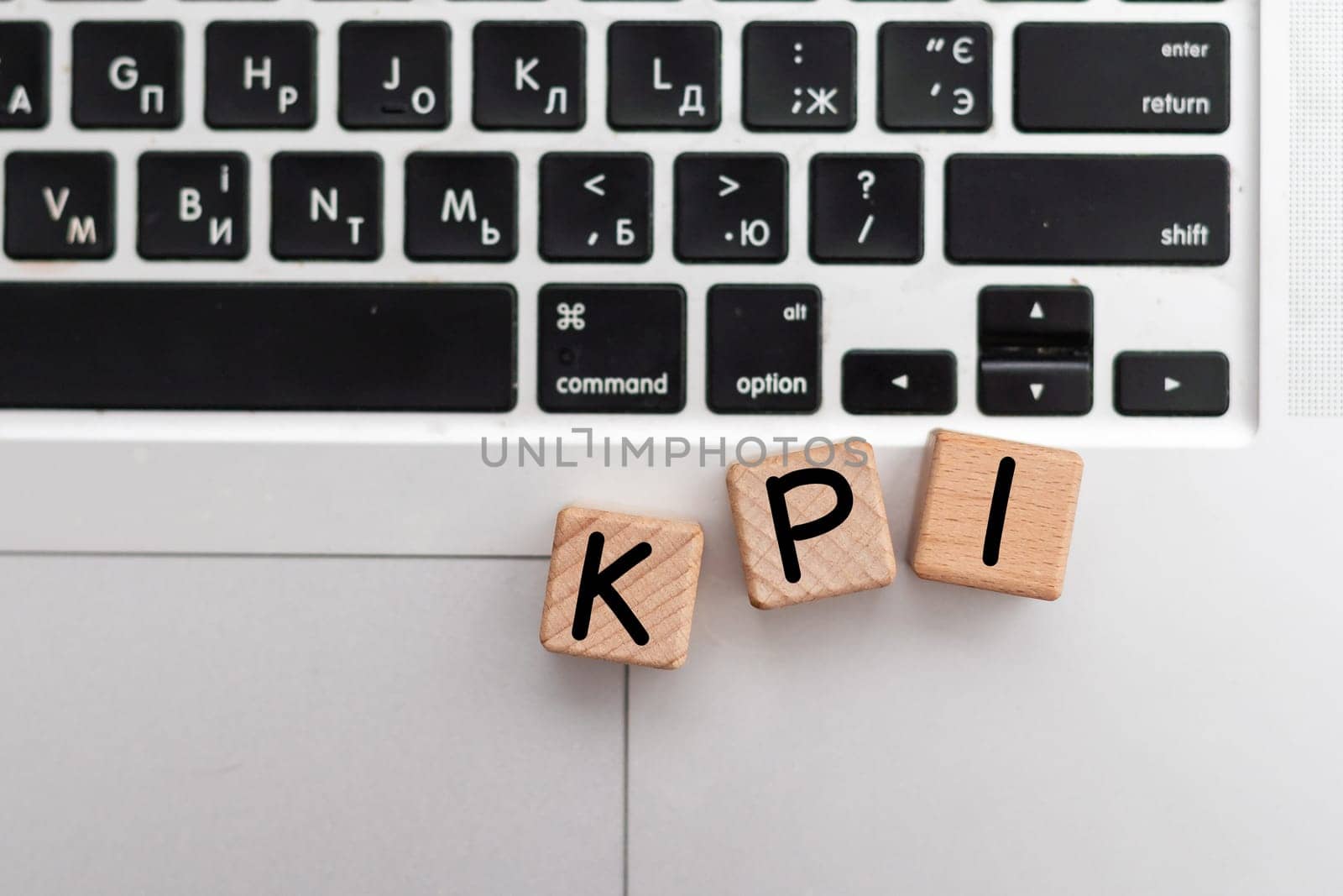 wooden blocks with KPI text of concept on laptop. High quality photo