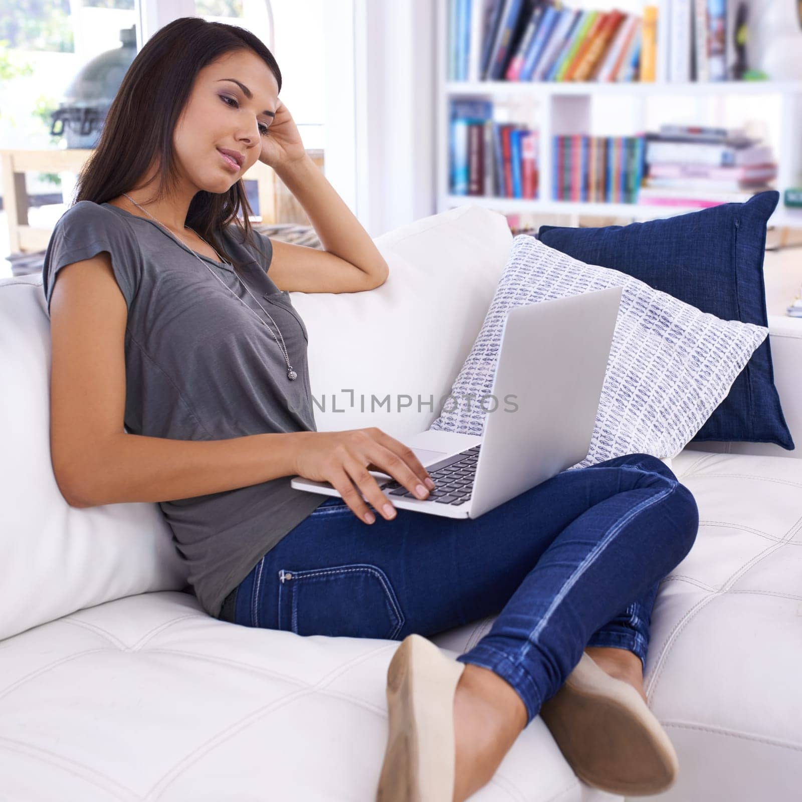 Woman, laptop and online in home for relax with typing email, communication and internet research in living room. Person, technology and social media search, web subscription or writing blog on couch.