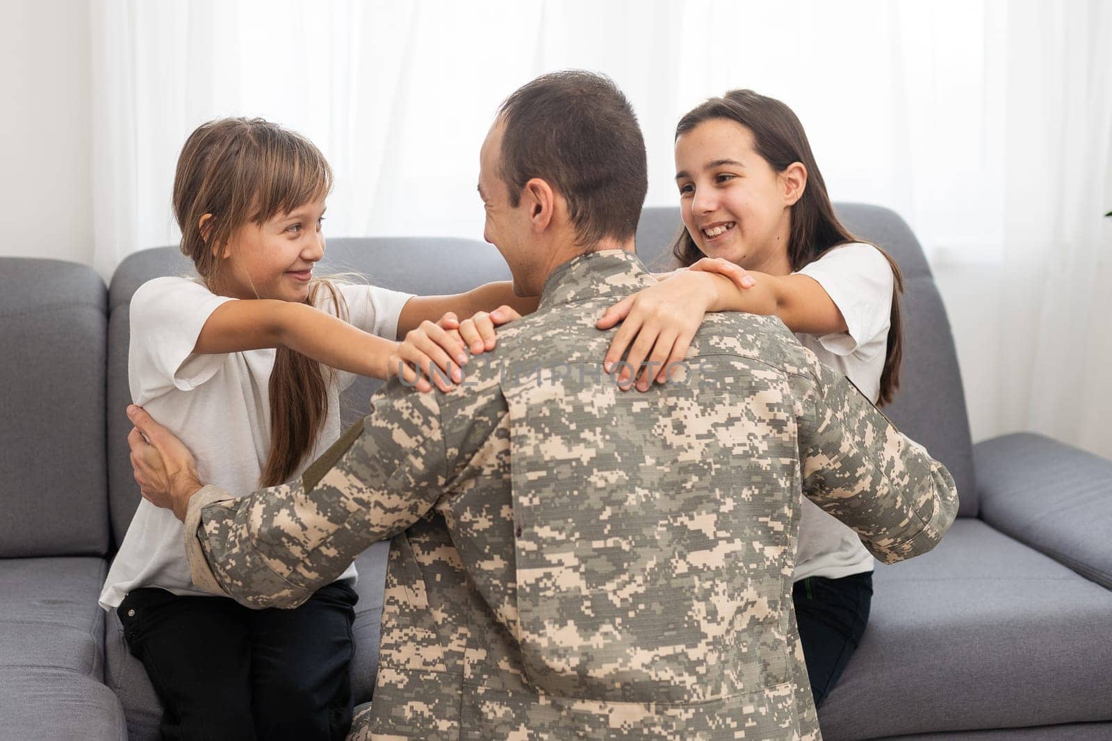 Little children hugging their military father at home by Andelov13